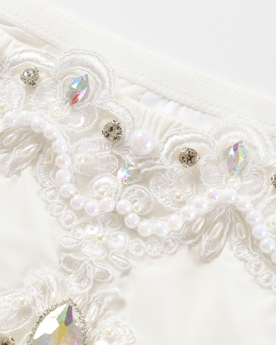 Close-up of Opheline - White - Bottom fabric with embroidered floral patterns, faux pearls, sequins, and iridescent crystal beads.