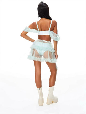 A woman stands with her back to the camera against a white background, wearing The Princess- Dream from the Sky Green: a sheer light green skirt and matching bralette, paired with white platform boots and elegant satin princess gloves.