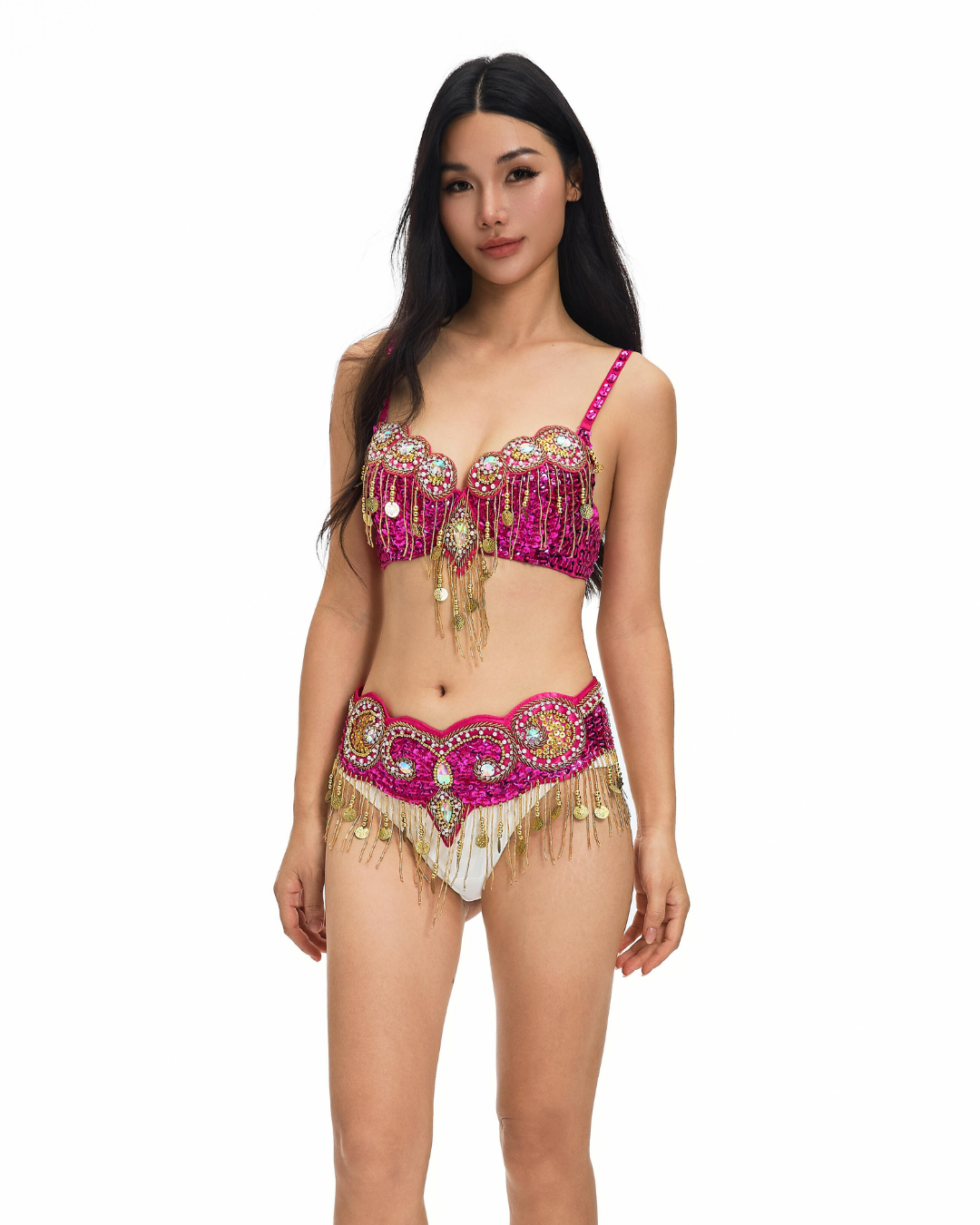A woman stands facing forward, wearing the Notics-Full Set- Rosé belly dance costume, featuring pink and gold embellishments with fringe details, against a plain white background.
