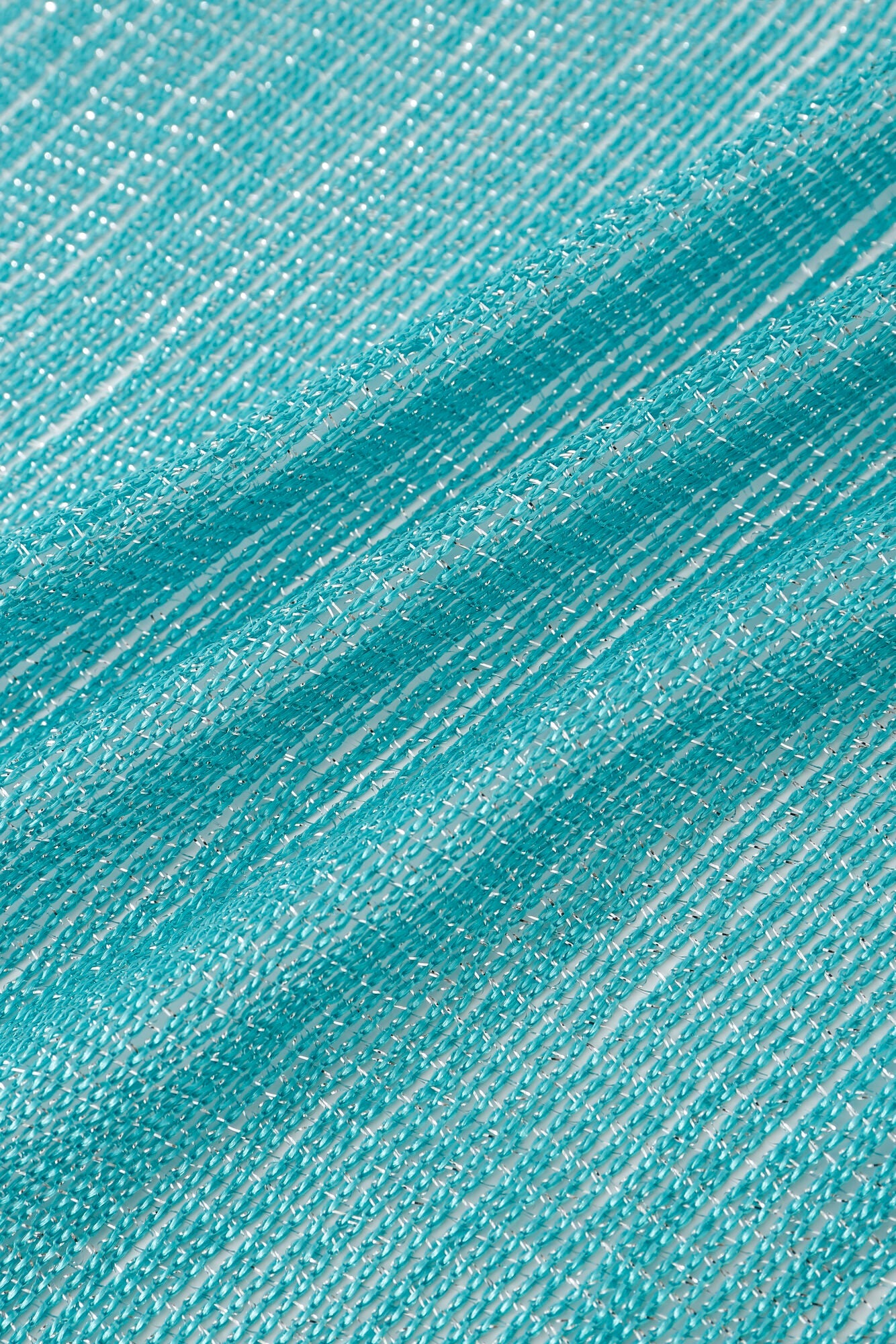Close-up of the Pashmina - Aqua Solid Fringe, showcasing textured turquoise fabric with horizontal and diagonal threads forming a wavy pattern.