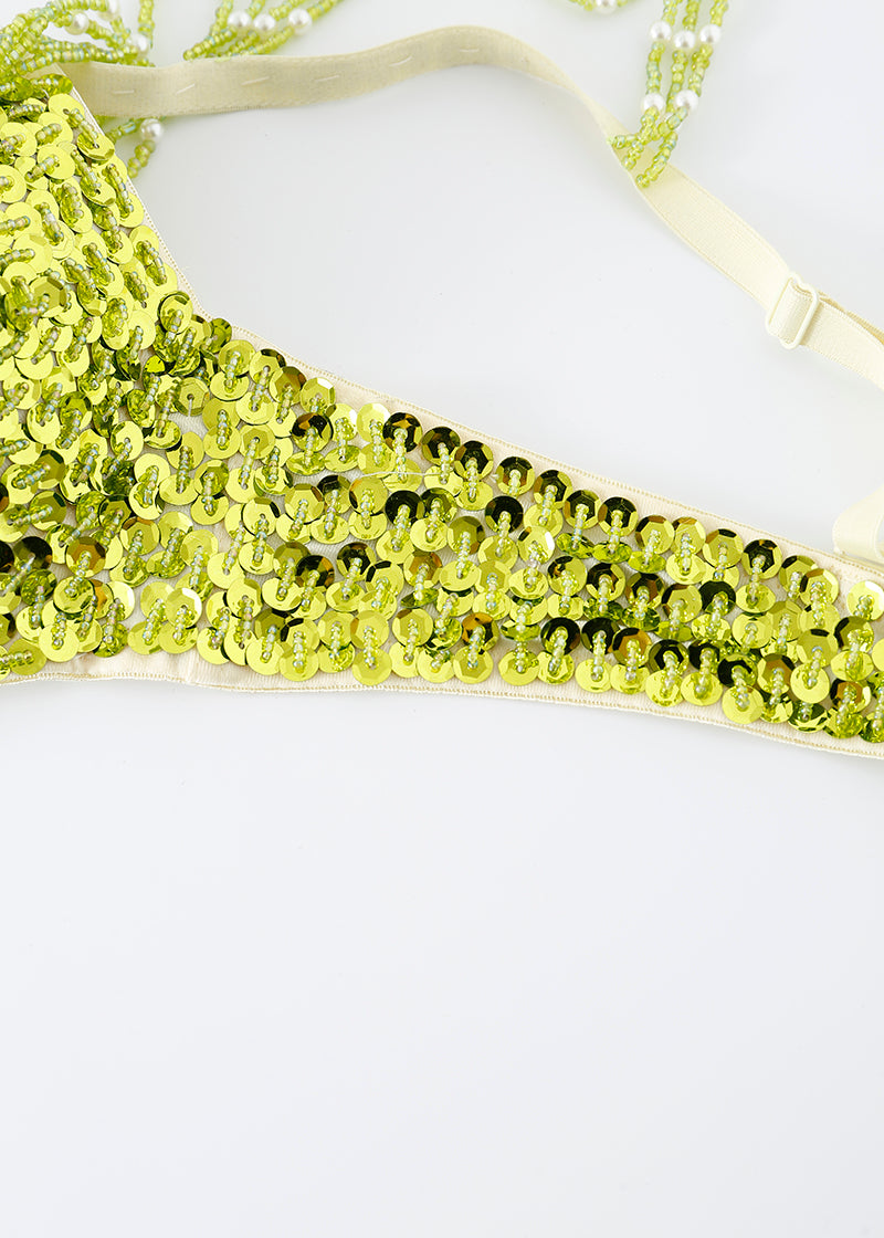 Close-up of the Venya - Lime Green - Top, a sequin bra perfect for rave festivals, paired with a matching yellow bikini bottom featuring adjustable straps, all displayed on a plain white background.