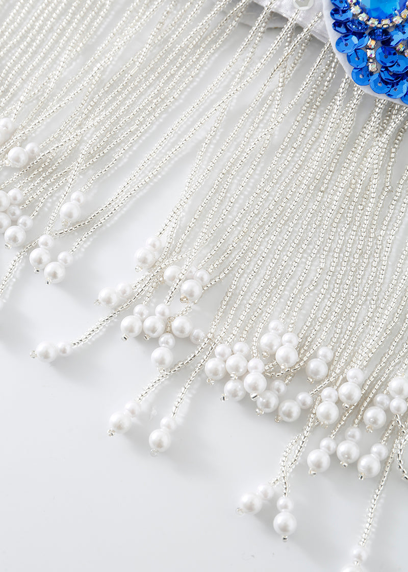 Close-up of white beaded fringe with pearl-like beads hanging from fine threads, attached to blue sequin fabric—an ideal accent for the Imperya - Silver - Bottom, creating show-stopping rave festival wear.