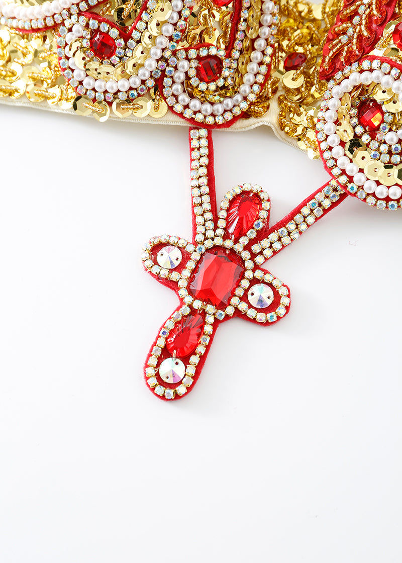 Close-up of the Imperya - Gold - Top, embellished with gold, red, and white beads and gems in an intricate pattern—ideal for festival wear or as a standout rave outfit, shown against a white background.