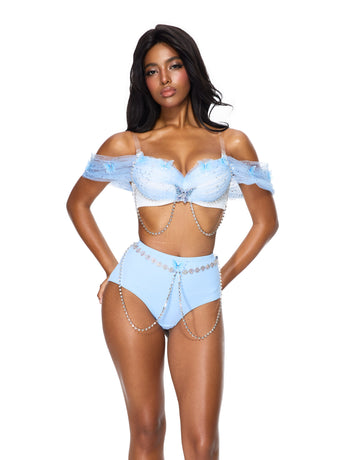 Wearing the “Dream from the Sky - Full Set - White Blue,” a light blue off-shoulder bra top paired with high-waisted shorts adorned with chain and bead embellishments, she stands against a white background—showcasing a stunning handmade rave wear look perfect for any festival.
