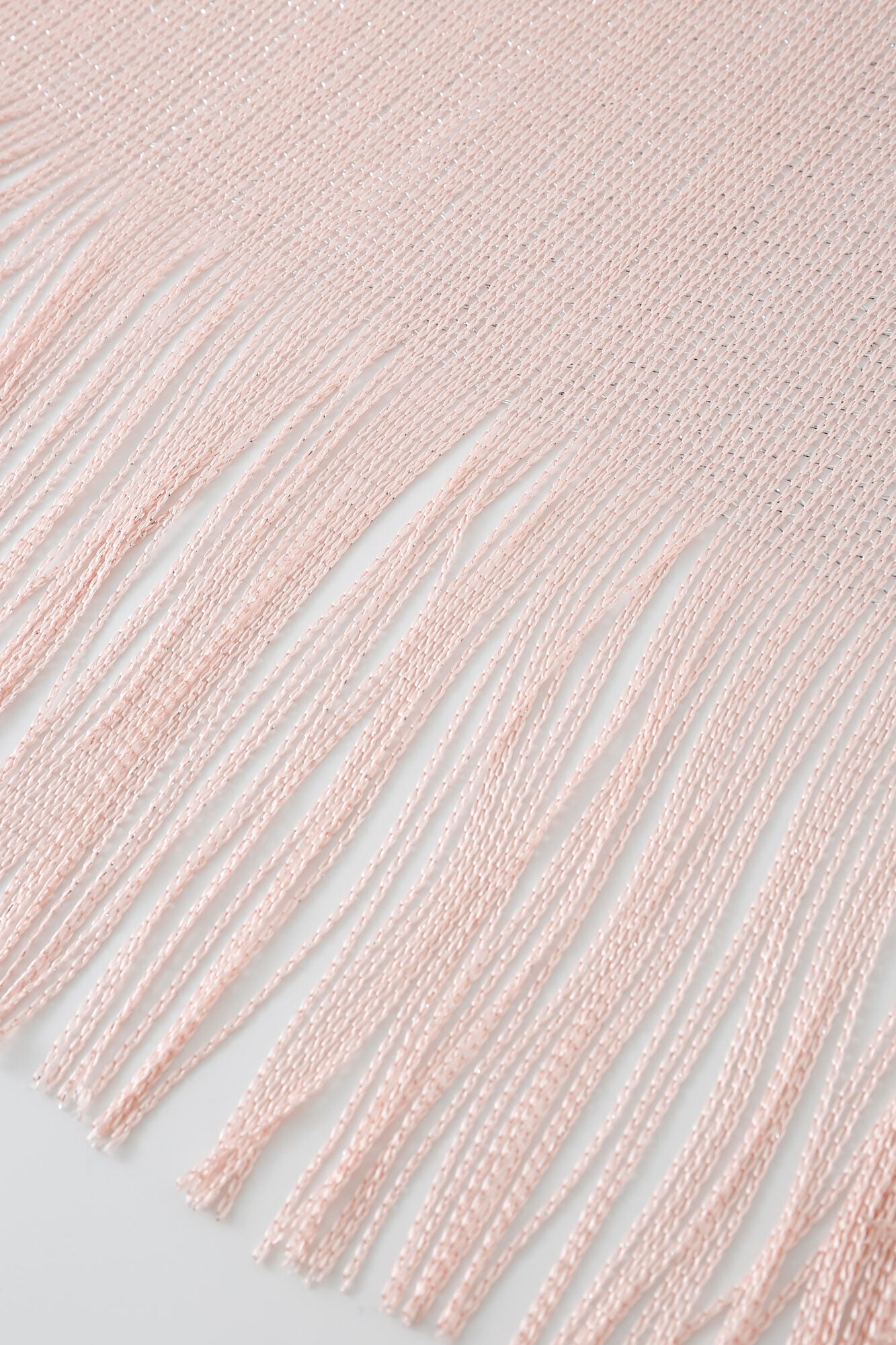 Close-up of the Pashmina - Blush Sheer Fringe, featuring light pink, evenly spaced long fringe threads extending from the edge and laid flat on a white surface.