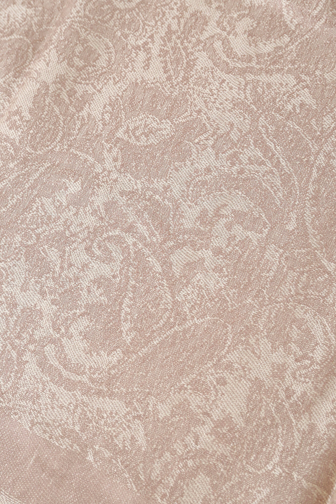 Close-up of the Pashmina - Champagne Paisley Fringe, showcasing its beige fabric with an intricate, textured leaf and floral pattern woven throughout.