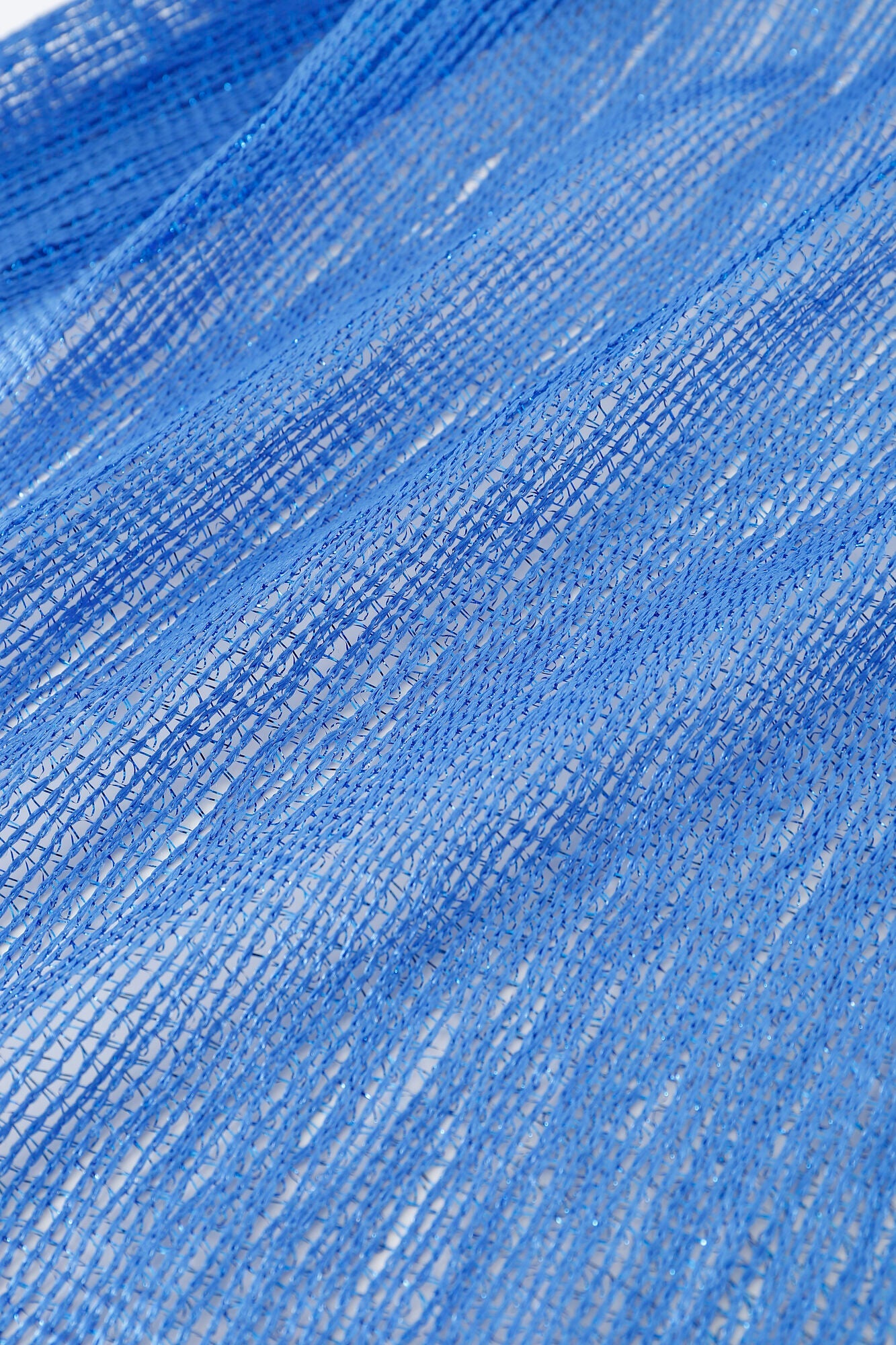 Close-up of the Pashmina - Cobalt Solid Fringe, a blue loosely woven mesh fabric with visible gaps and threads, set against a white background.