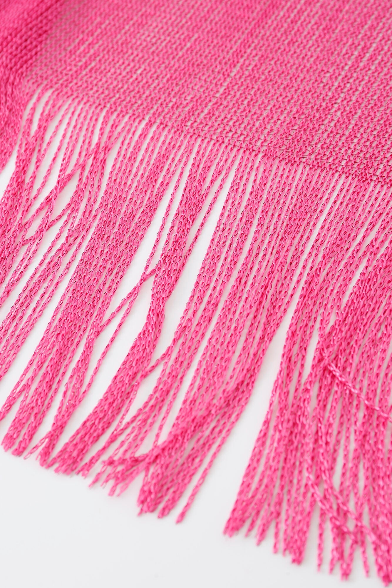 Close-up of the Pashmina - Fuchsia Solid Fringe, featuring woven pink fabric with long, loose fringe at the edge against a white background.