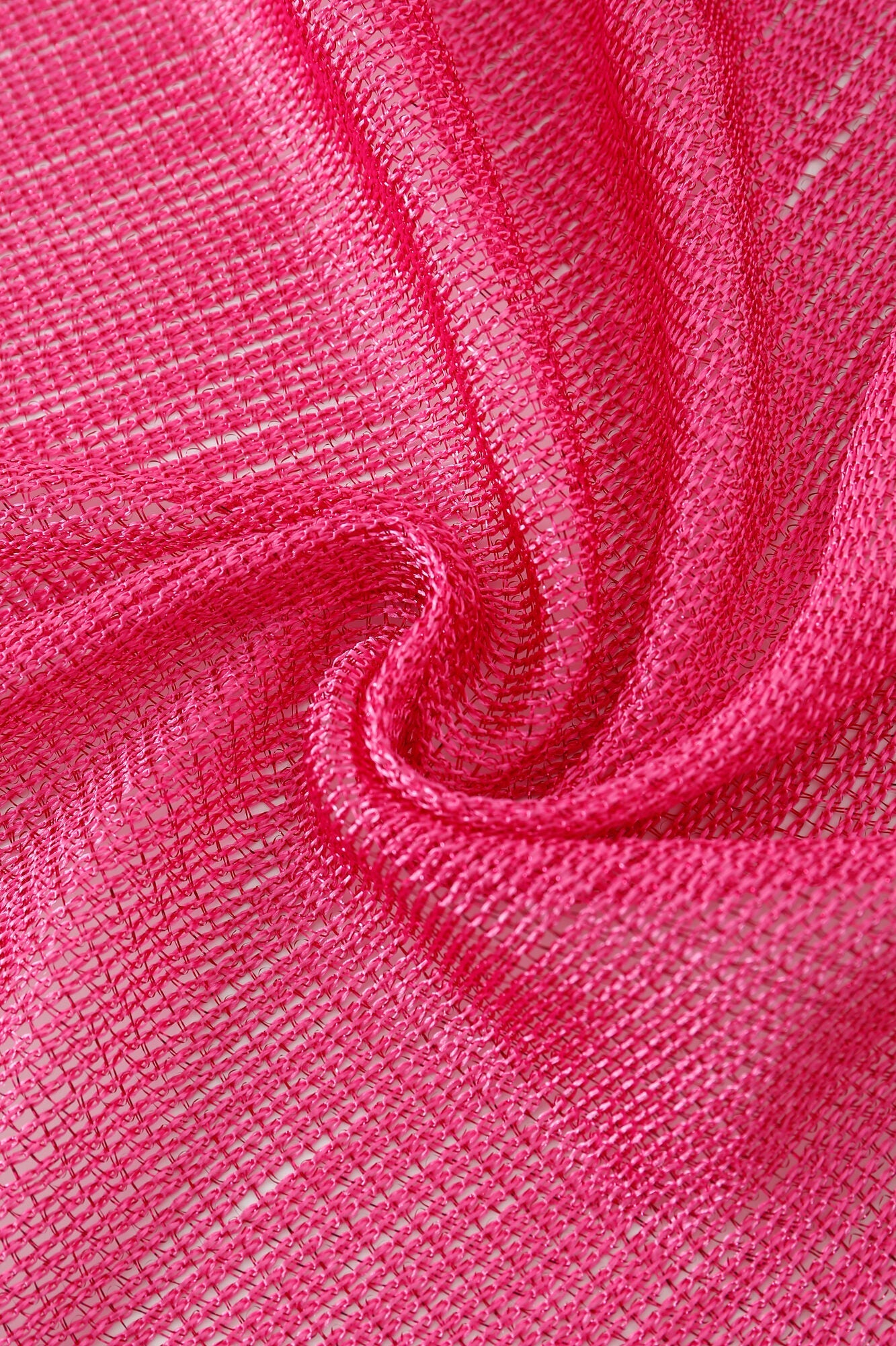 Close-up of the Pashmina - Fuchsia Solid Fringe: bright pink, semi-transparent fabric with a loose weave, twisted into a swirl pattern.