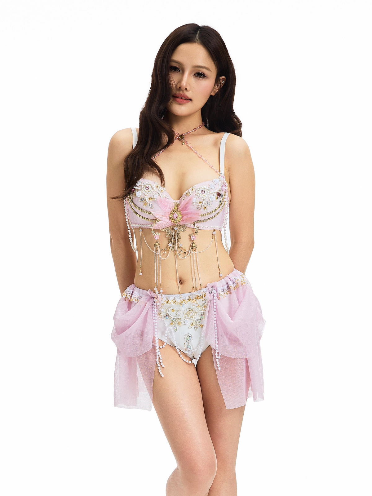 A woman stands against a white background wearing the GOSSAMER- FULL SET- PINK, an ornate lingerie set with pearl embellishments—perfect handmade festival wear.