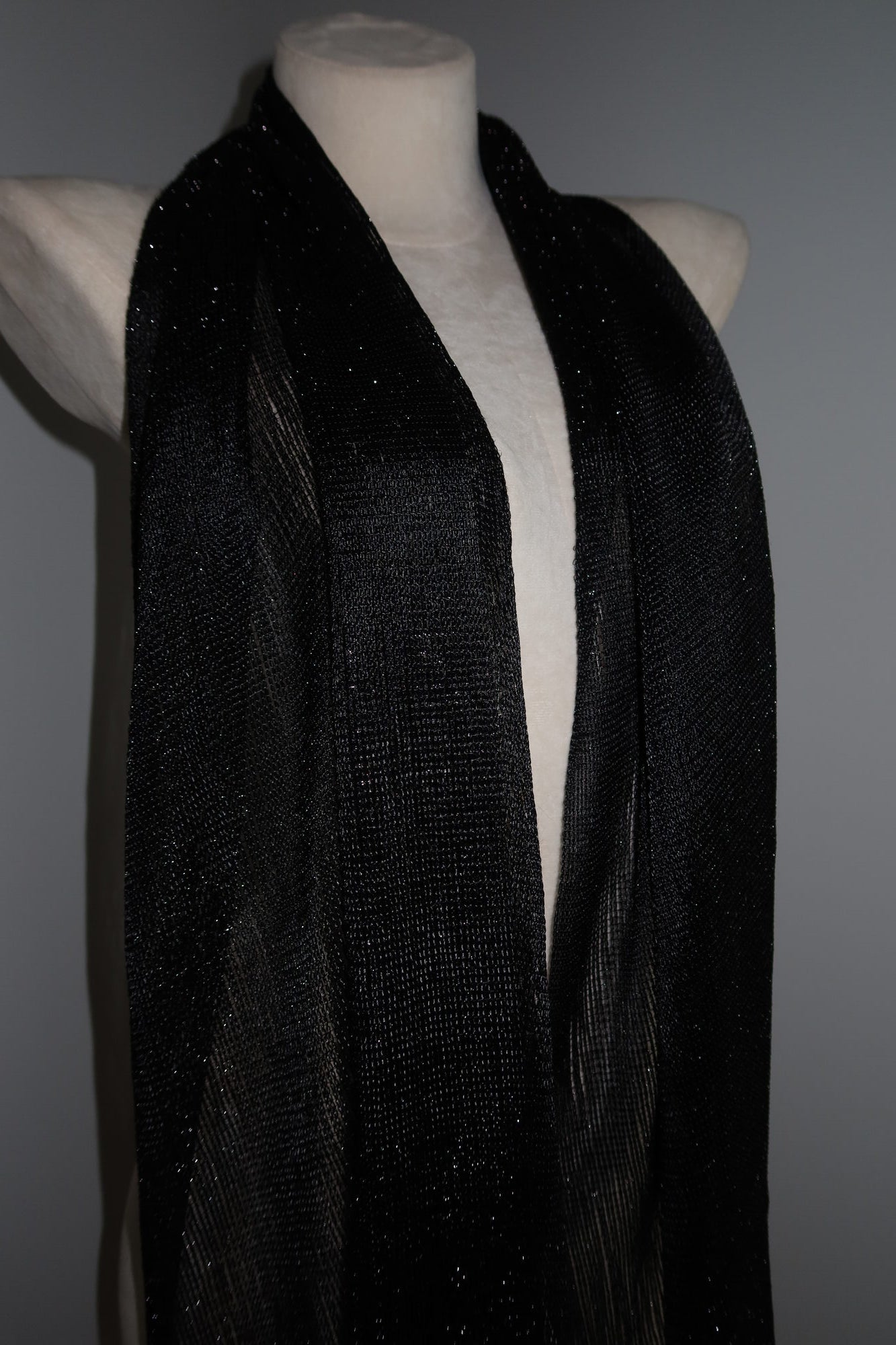 A mannequin showcases the Pashmina - Black Sheer Fringe draped around its neck, offering a shimmery, chic accessory perfect as a festival wrap for music events and stylish festival fashion.
