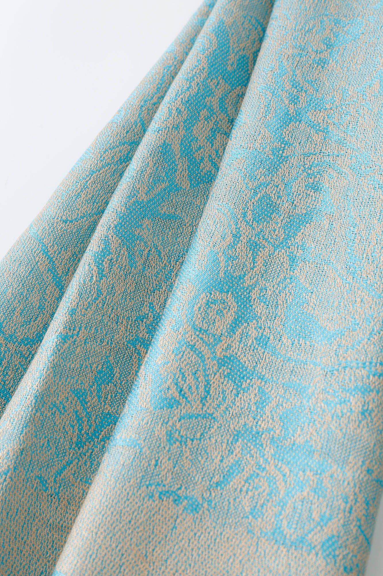 Close-up of the Pashmina - Ice Blue Paisley, highlighting its light blue fabric with a beige paisley jacquard pattern and intricate texture.