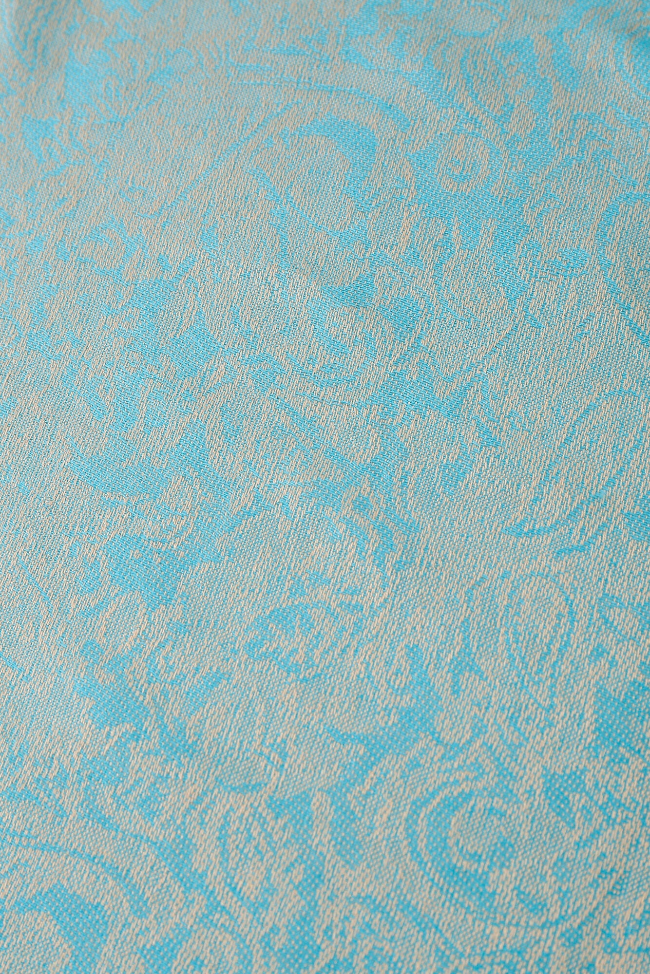 Close-up of Pashmina - Ice Blue Paisley, featuring light blue fabric with a raised, intricate paisley and vine pattern in a slightly lighter shade.