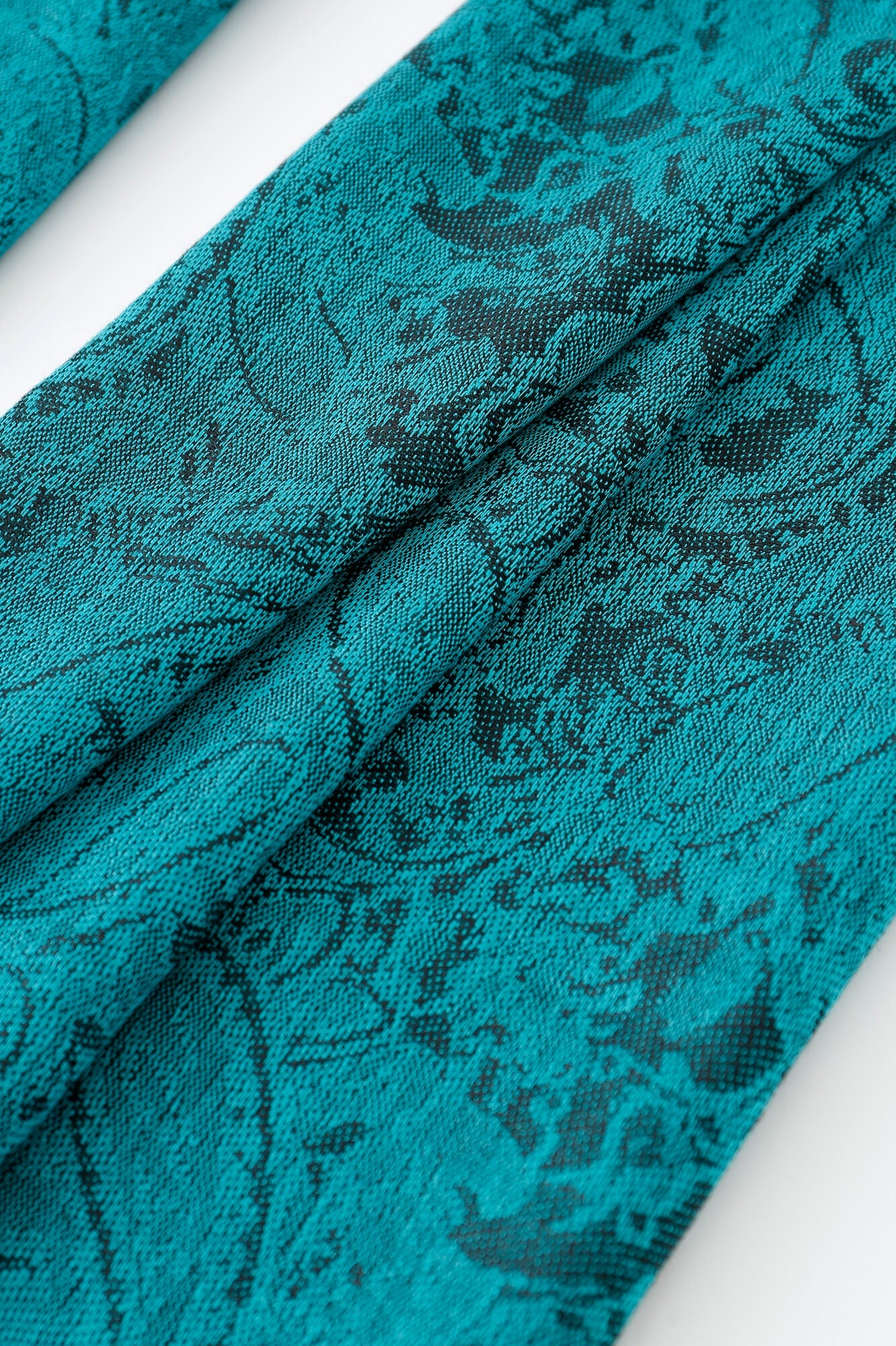 Close-up of the Pashmina - Peacock Paisley Fringe in teal, featuring a black abstract pattern that highlights the texture and intricate woven details.