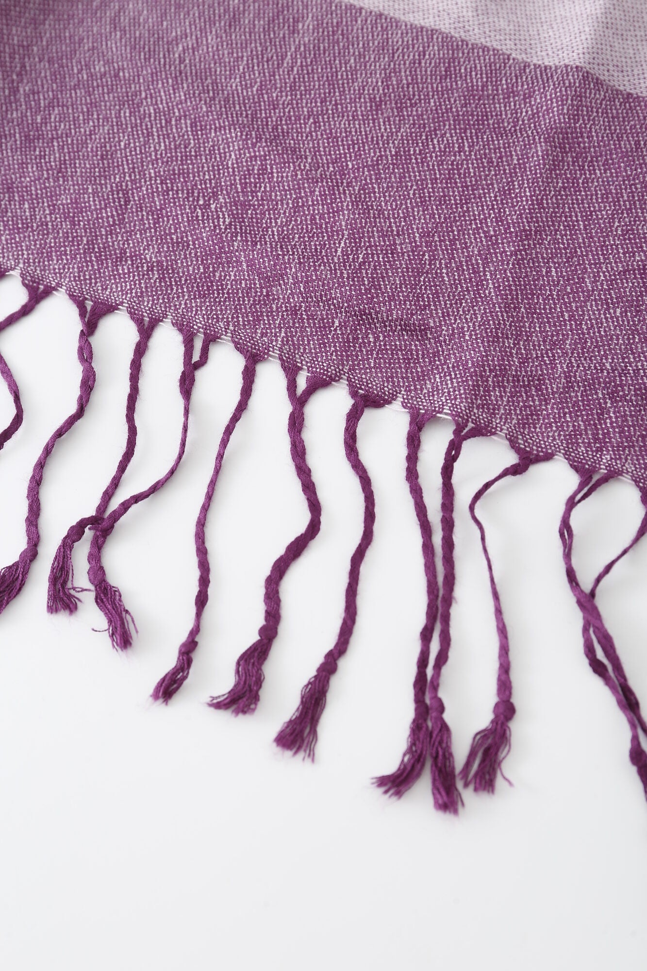 Close-up of the Pashmina - Purple Paisley Fringe, showcasing its purple woven fabric and twisted fringe tassels against a white background.