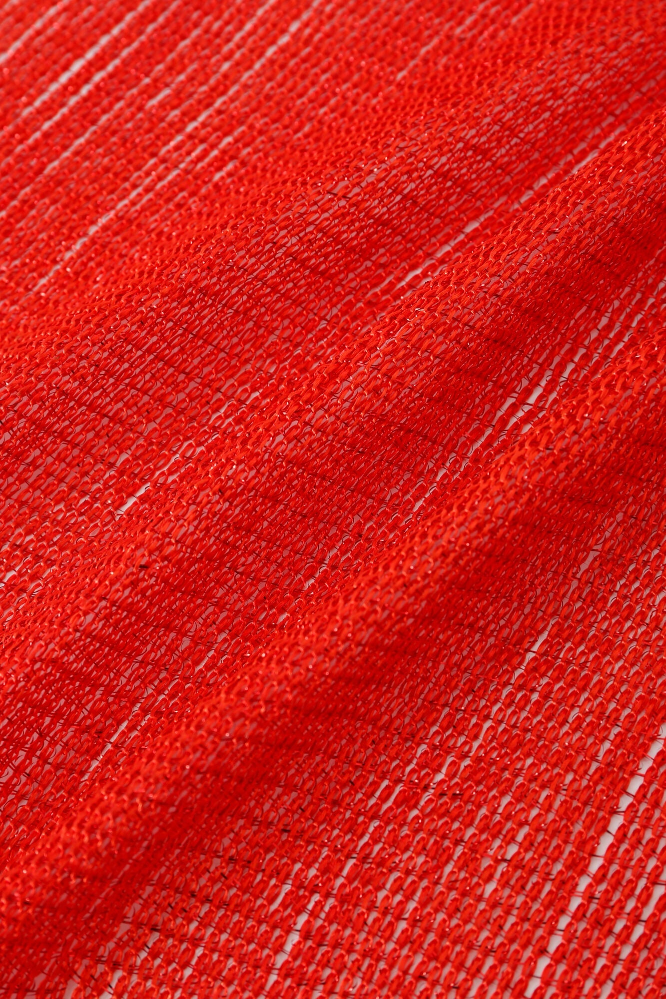 Close-up of the Pashmina - Scarlet Fringe shows red mesh fabric with a loose, open weave and visible strands.