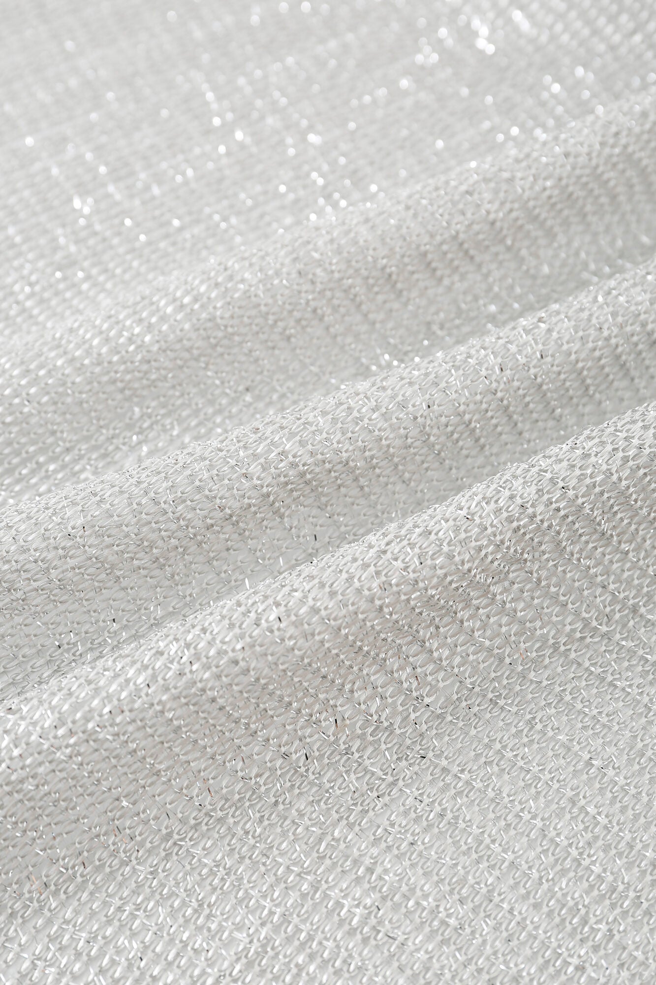 Close-up of Pashmina - Silver Sheer Fringe, featuring white woven fabric with a textured, slightly metallic shimmer, subtle folds, and a detailed weave pattern.