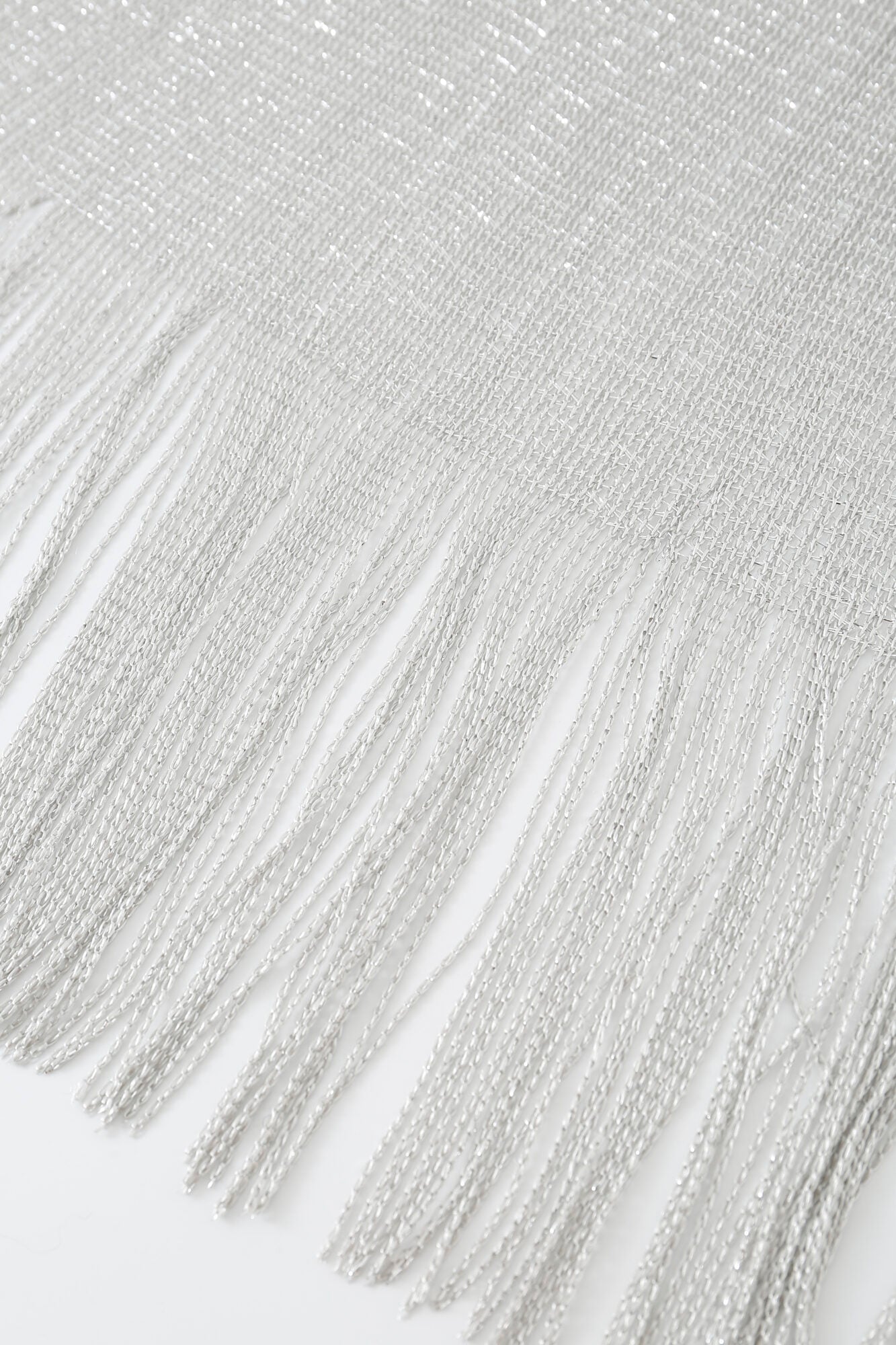 The Pashmina - Silver Sheer Fringe features elegant silver fringe accents elegantly hanging from a textured sheer fabric.