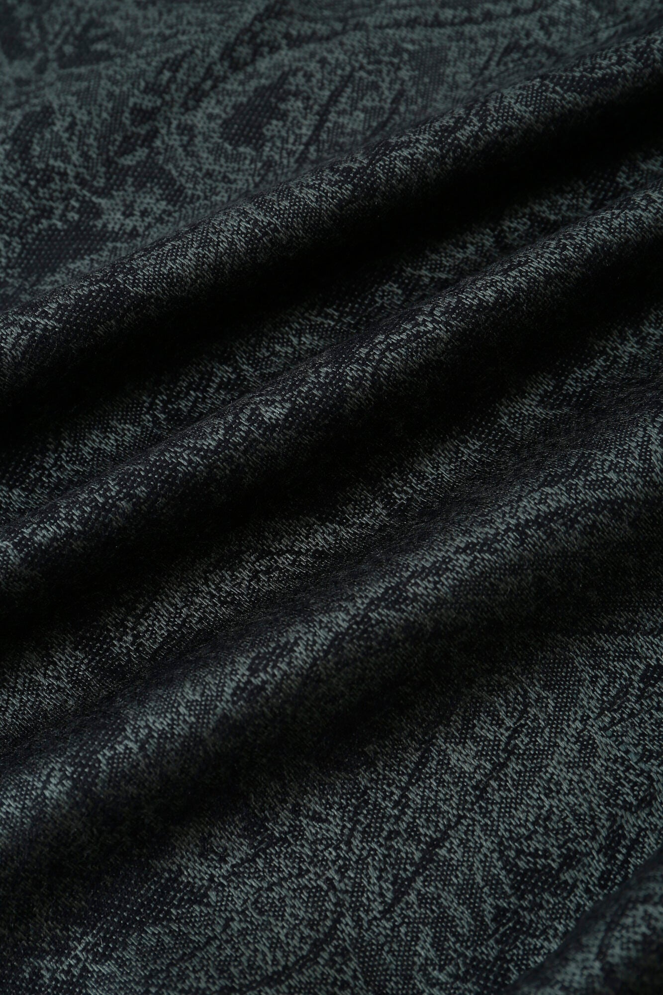 Close-up of the Pashmina - Slate Paisley Fringe, showing its dark, textured fabric with a subtle paisley pattern and gentle horizontal folds.