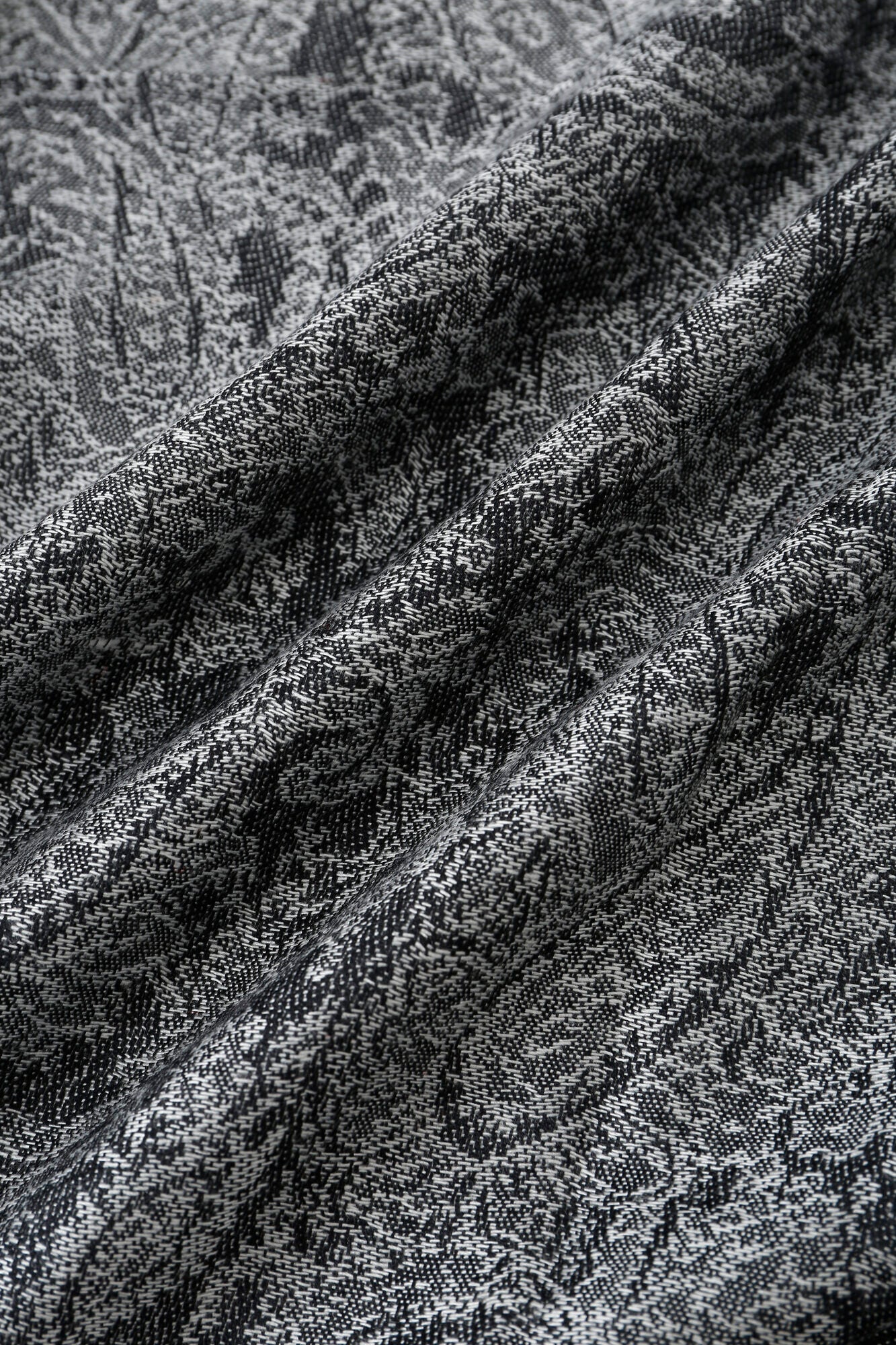 Close-up of the Pashmina - Smoky Paisley Fringe, featuring gray and black fabric with a textured, intricate paisley pattern and visible folds.