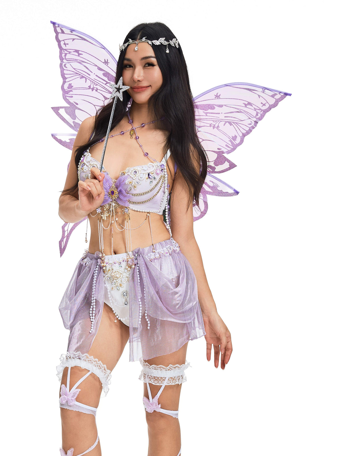 A woman dressed in a lavender fairy costume with wings, holding a star wand and wearing a jeweled headpiece, stands against a white background. Her whimsical look is completed with Butterfly Trap Purple Thigh Highs—a standout among rave accessories and festival stockings.