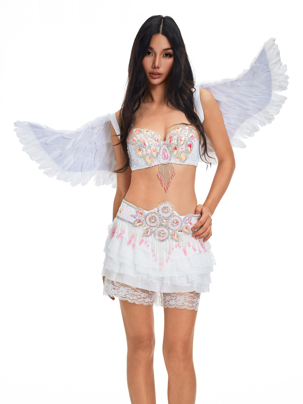 A woman models the “Angel Wings- White,” featuring elegant feather wings, a decorated bra, layered skirt, and lace shorts, all set against a plain white background.