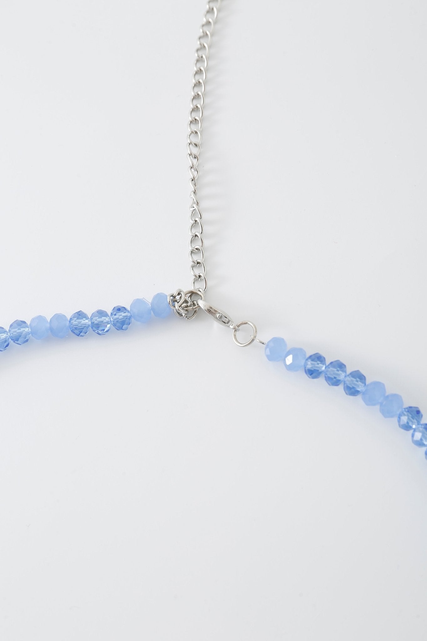 A close-up of the “Azura w Mini Skirt- Full Set” necklace, featuring small blue beads, rhinestone detailing, and a silver chain on a white background.