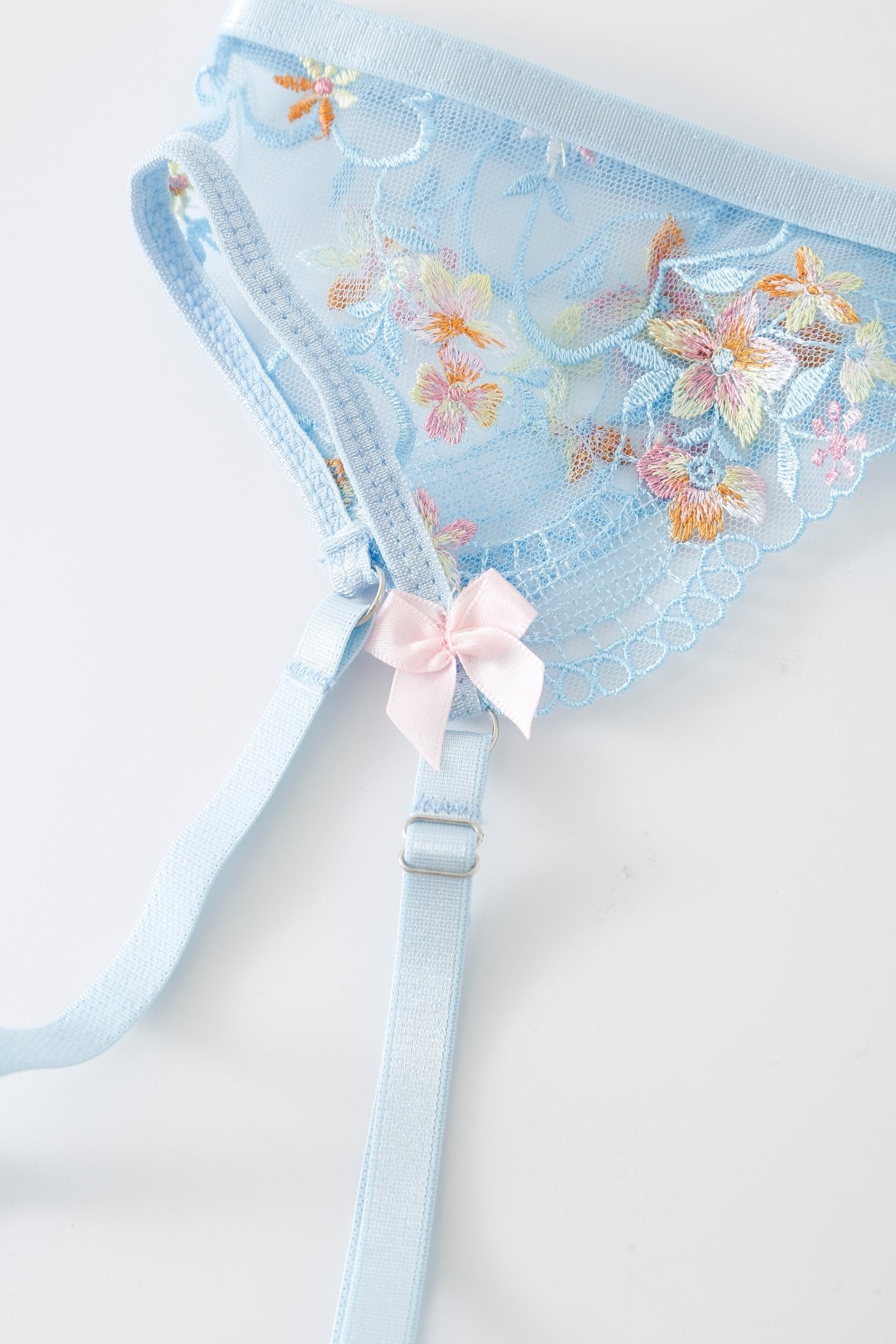 Azura w Mini Skirt - Full Set in light blue lace features floral embroidery, adjustable straps, and a small pink bow accent, shown on a white background.
