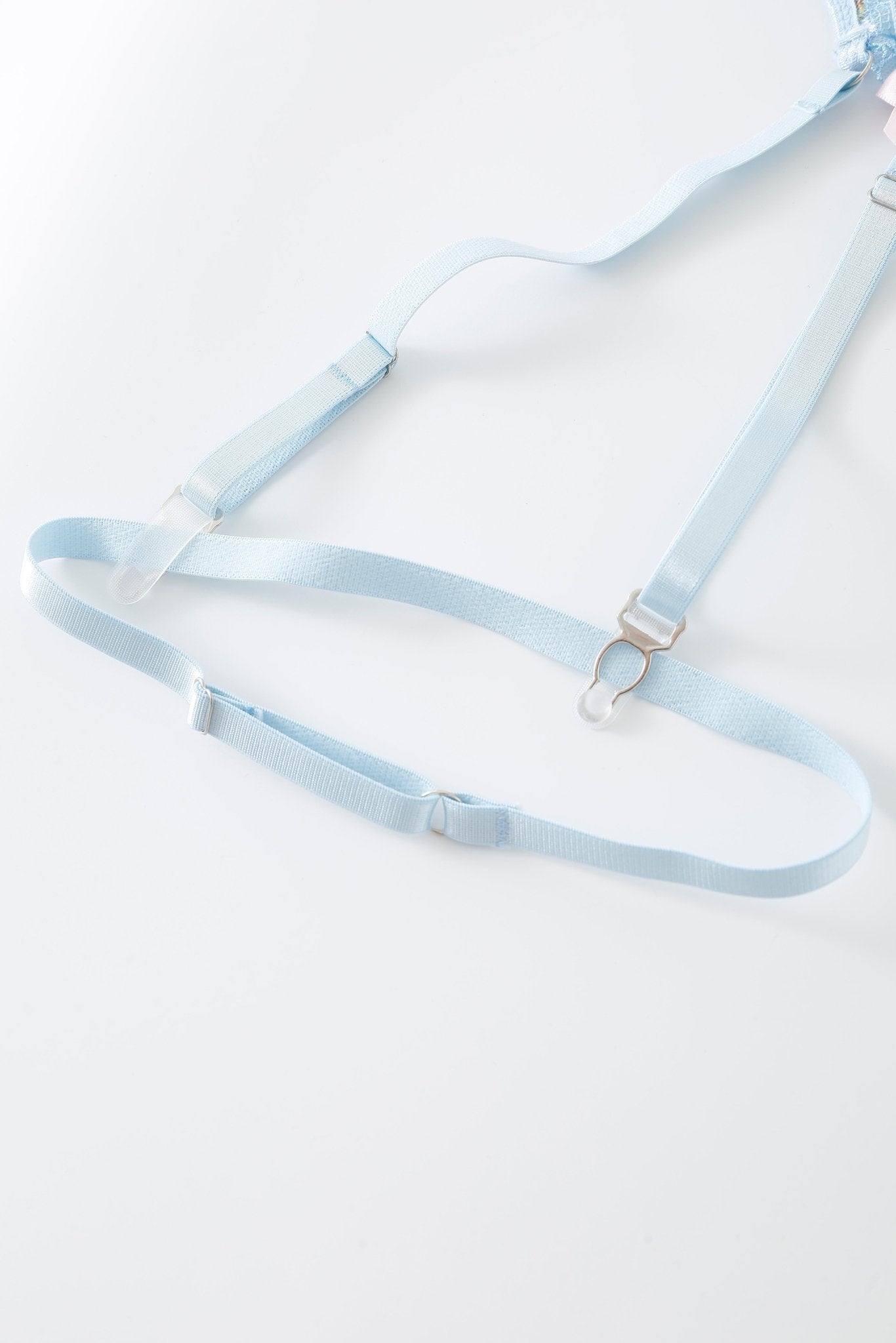 The Azura w Mini Skirt - Full Set, a light blue elastic garter belt with adjustable straps and metal clips, features delicate rhinestone detailing and is laid flat on a white surface.