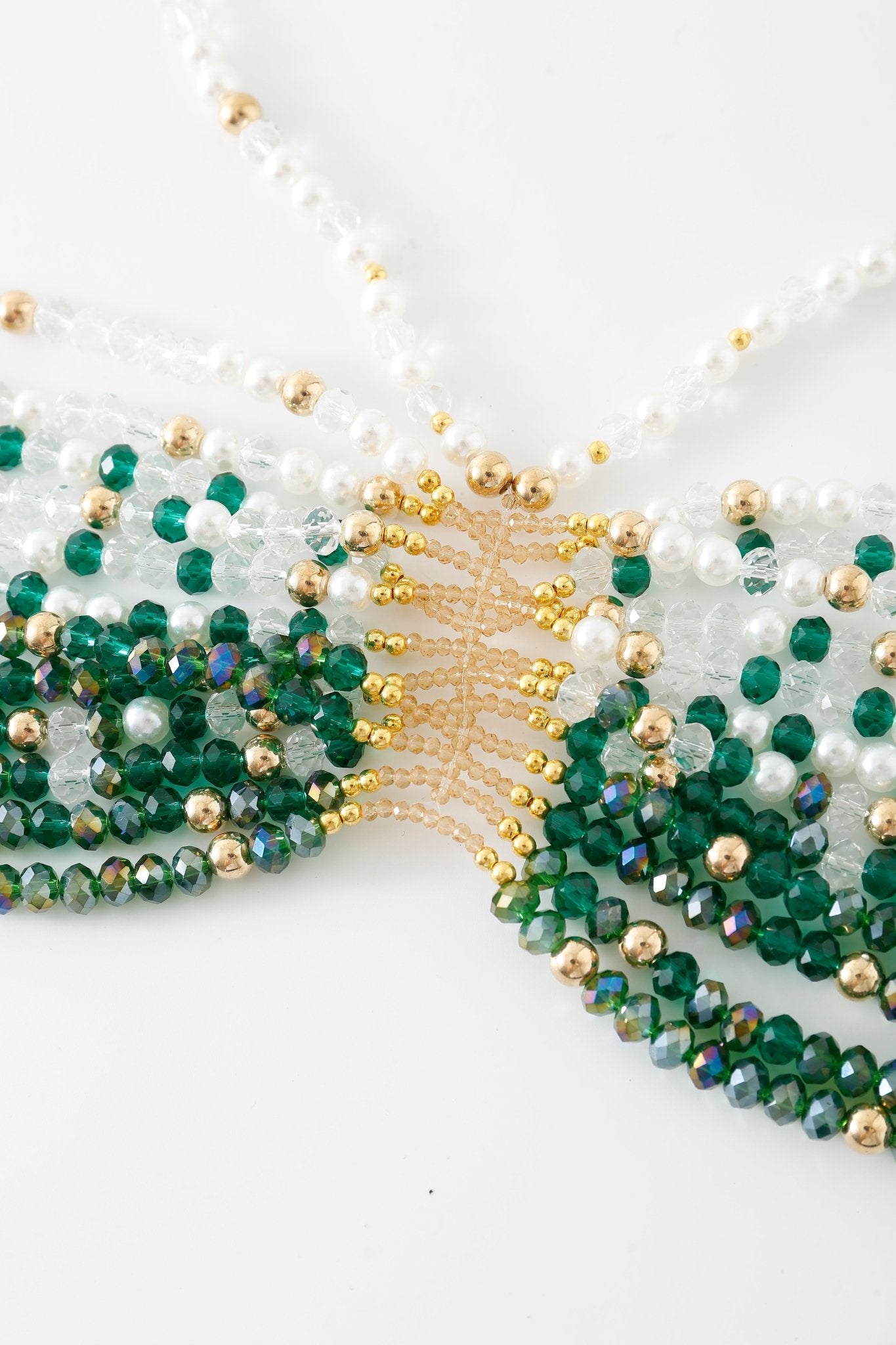 Close-up of the Eve w Pashmina - Full Set, featuring an intricately beaded necklace with green, gold, white, and iridescent beads arranged in a geometric pattern on a white background—reminiscent of the beautiful detailing found on a beaded top.