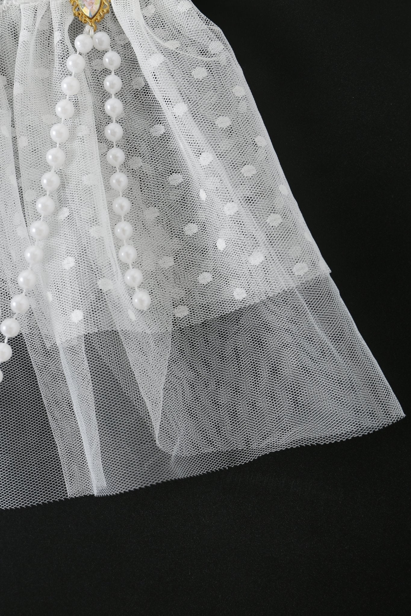 The Haló - White - Skirt features white polka dot tulle over a black base, accented with a strand of pearls—ideal for elevating your festival look or sparking inspiration for your next pearl feather costume.