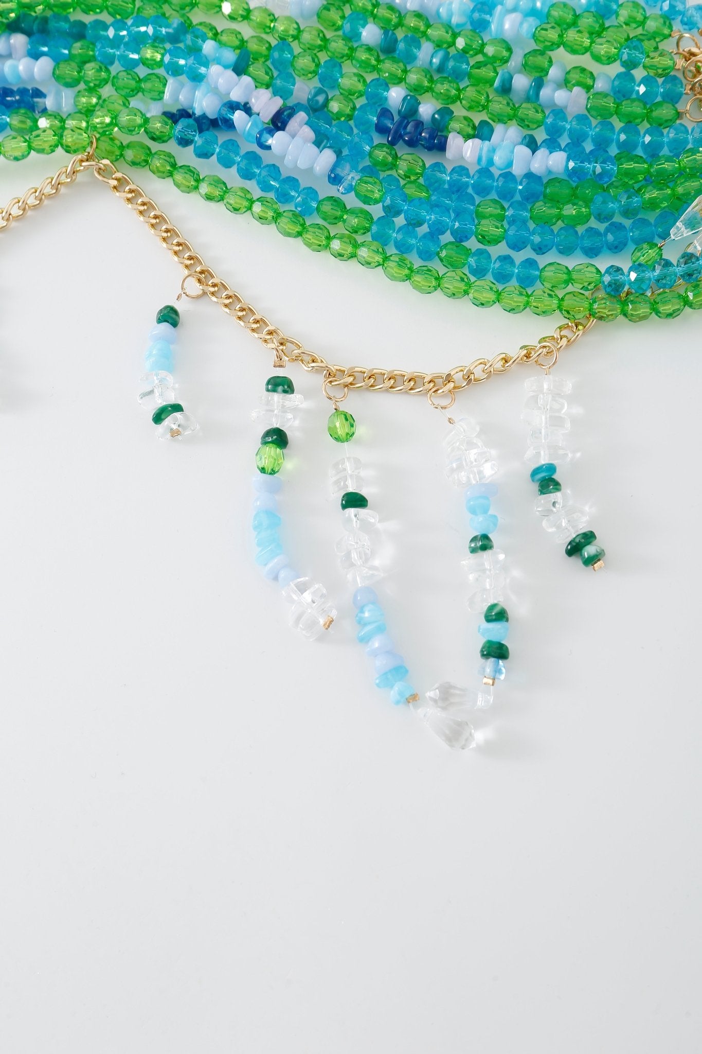 Lagoon w Pashmina- Full Set: A gold chain necklace featuring cascading strands of blue, green, and clear beads, displayed against a white background with additional beaded accents at the top, evoking the delicate look of a beaded top or the elegant fringe found on a pashmina wrap.