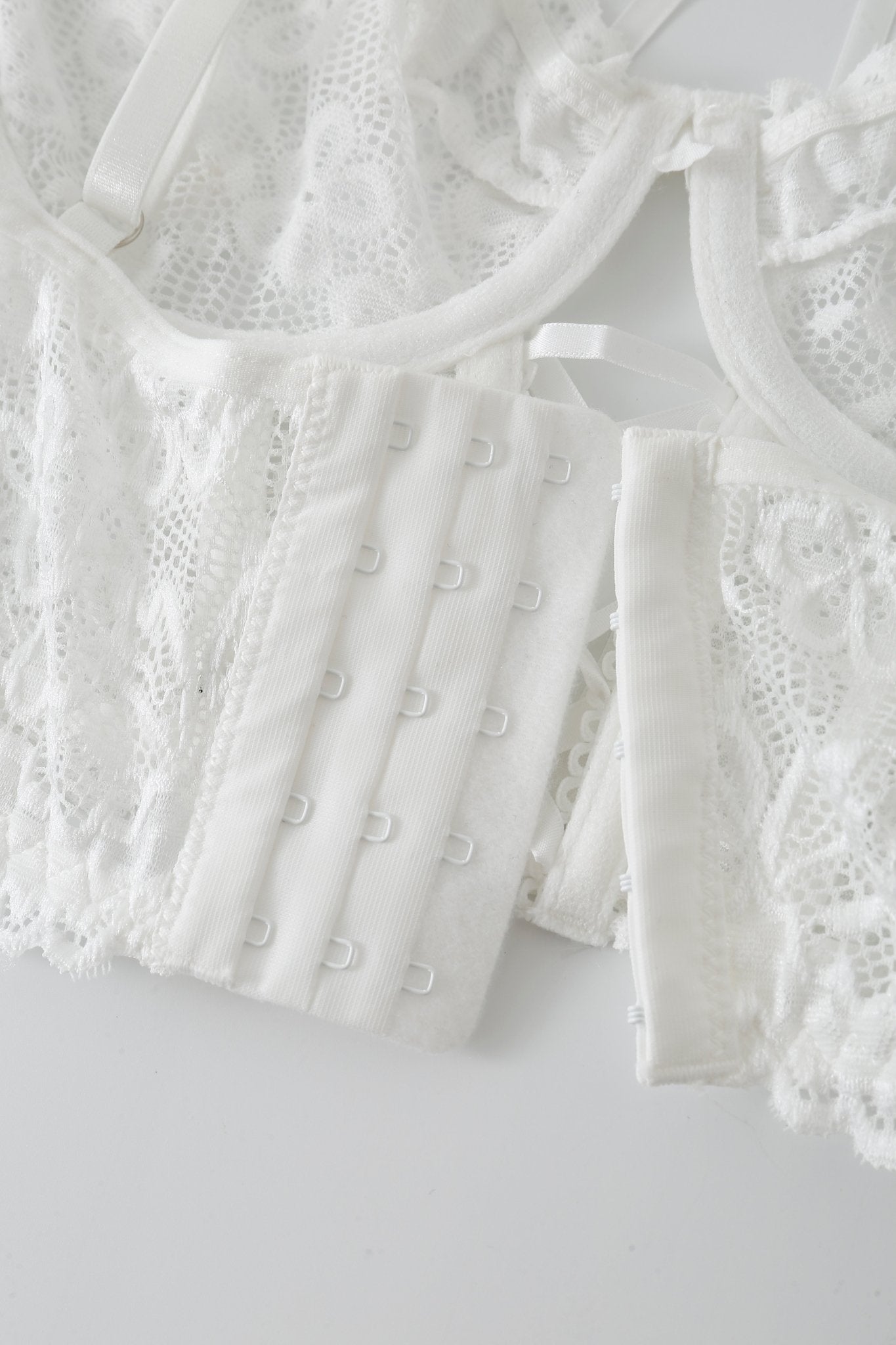 Close-up of the Mariposa w Pashmina- Full Set, featuring a white lace lingerie bra with adjustable hook-and-eye closures, laid flat on a white surface.