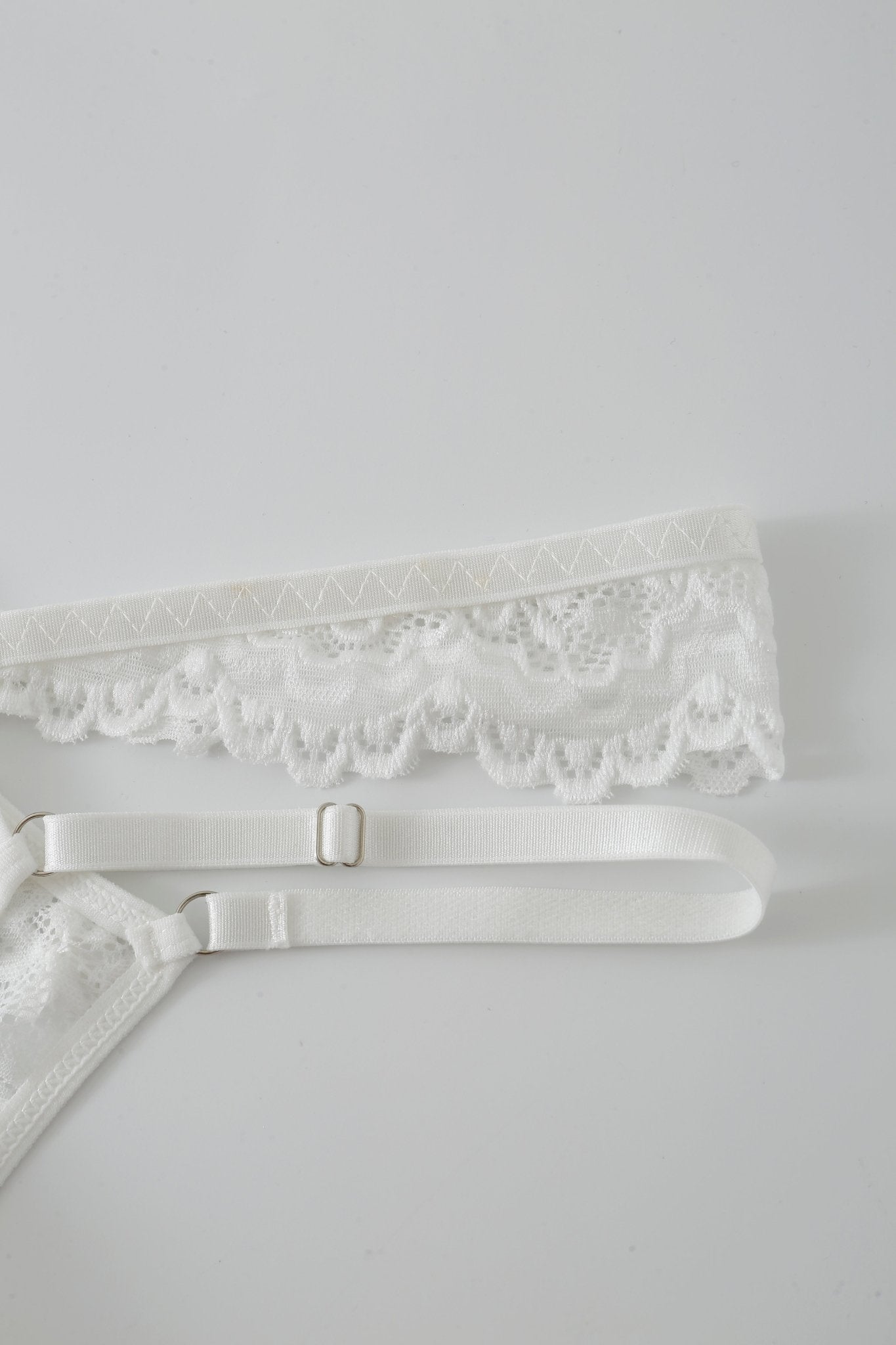 The Mariposa w Mini Skirt - Full Set features white lace lingerie with a decorative waistband and adjustable straps, presented against a plain white background—ideal for pairing with the matching mesh mini skirt for a striking festival look or as an elegant addition to the Mariposa lingerie collection.