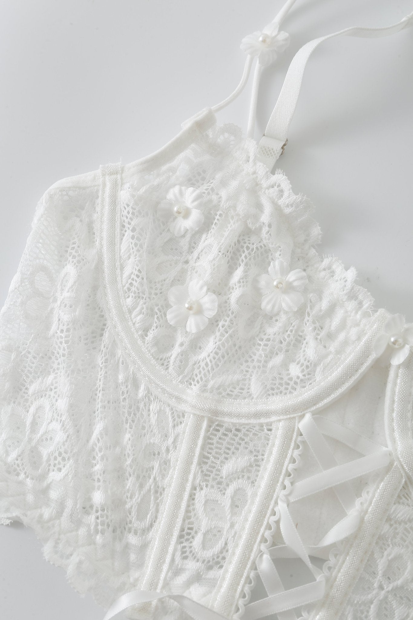 The Mariposa w Pashmina—Full Set features a white lace bralette adorned with floral embroidery and pearl accents, designed with thin straps and a delicate, sheer style that’s perfect for layering under the coordinating fringe pashmina wrap or mixing and matching with other Mariposa lingerie pieces.
