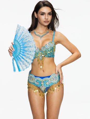 A woman wears the Notics - Aqua - Top, an ornate blue and gold belly dance costume with crystal embellishments, holding a matching fan against a plain white background.