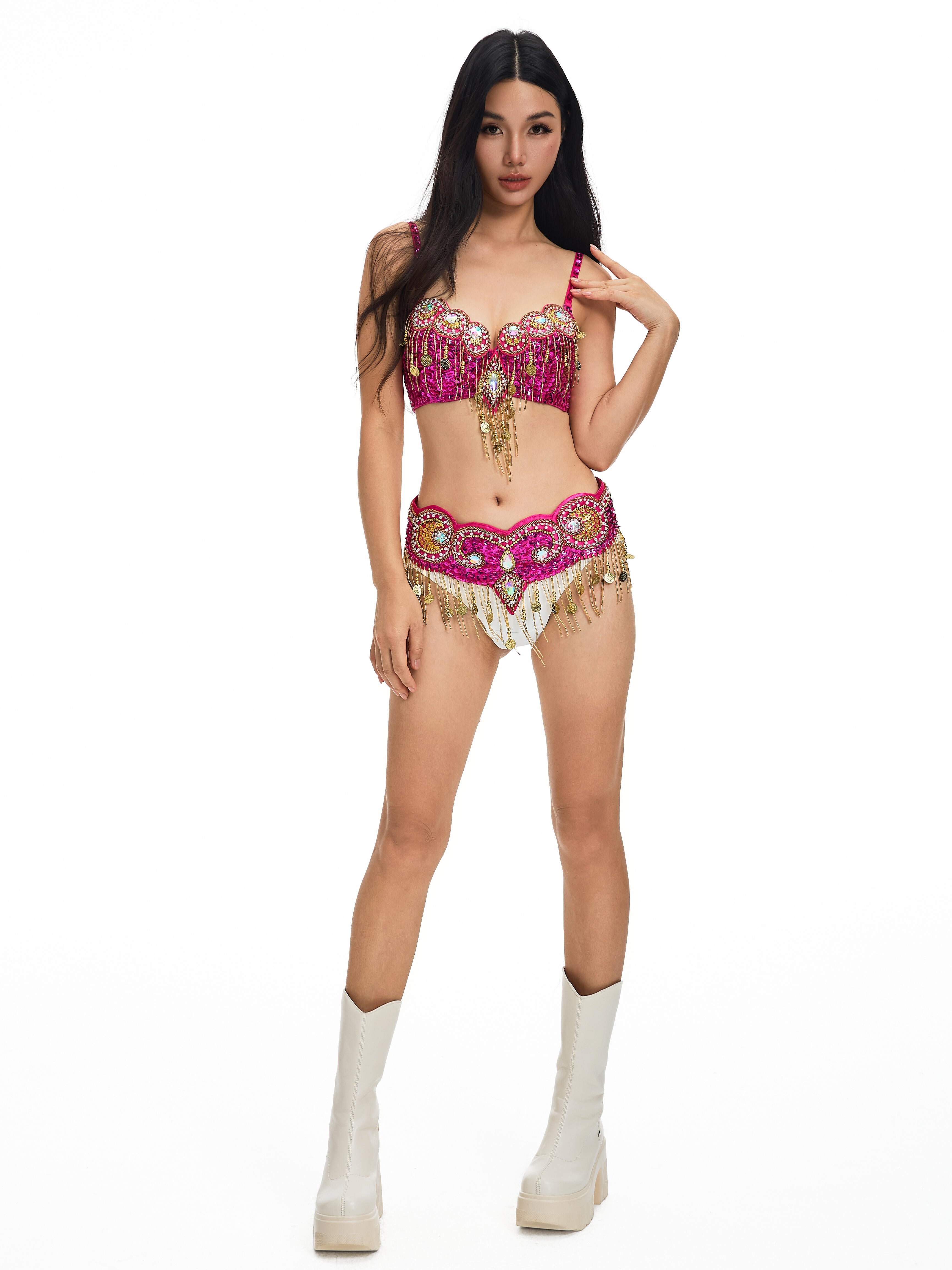 A woman stands on a white background wearing the Notics-Full Set- Rosé, featuring a pink and gold embellished bra and shorts set paired with white platform boots.
