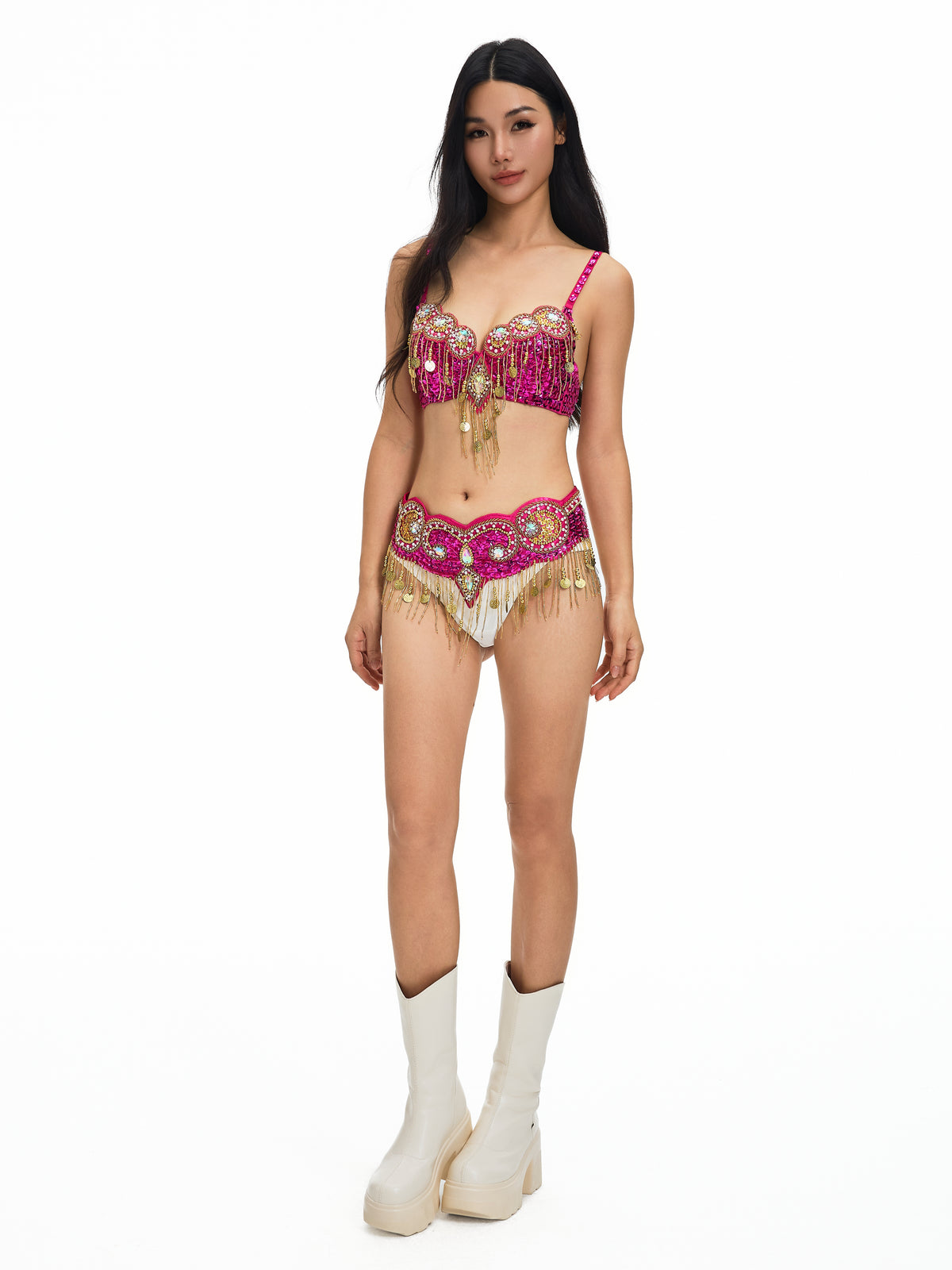 Woman standing against a white background, wearing the Notics- Rosé- Top—a pink and gold fringed piece—paired with white platform boots for a striking festival outfit that’s perfect for making a statement.