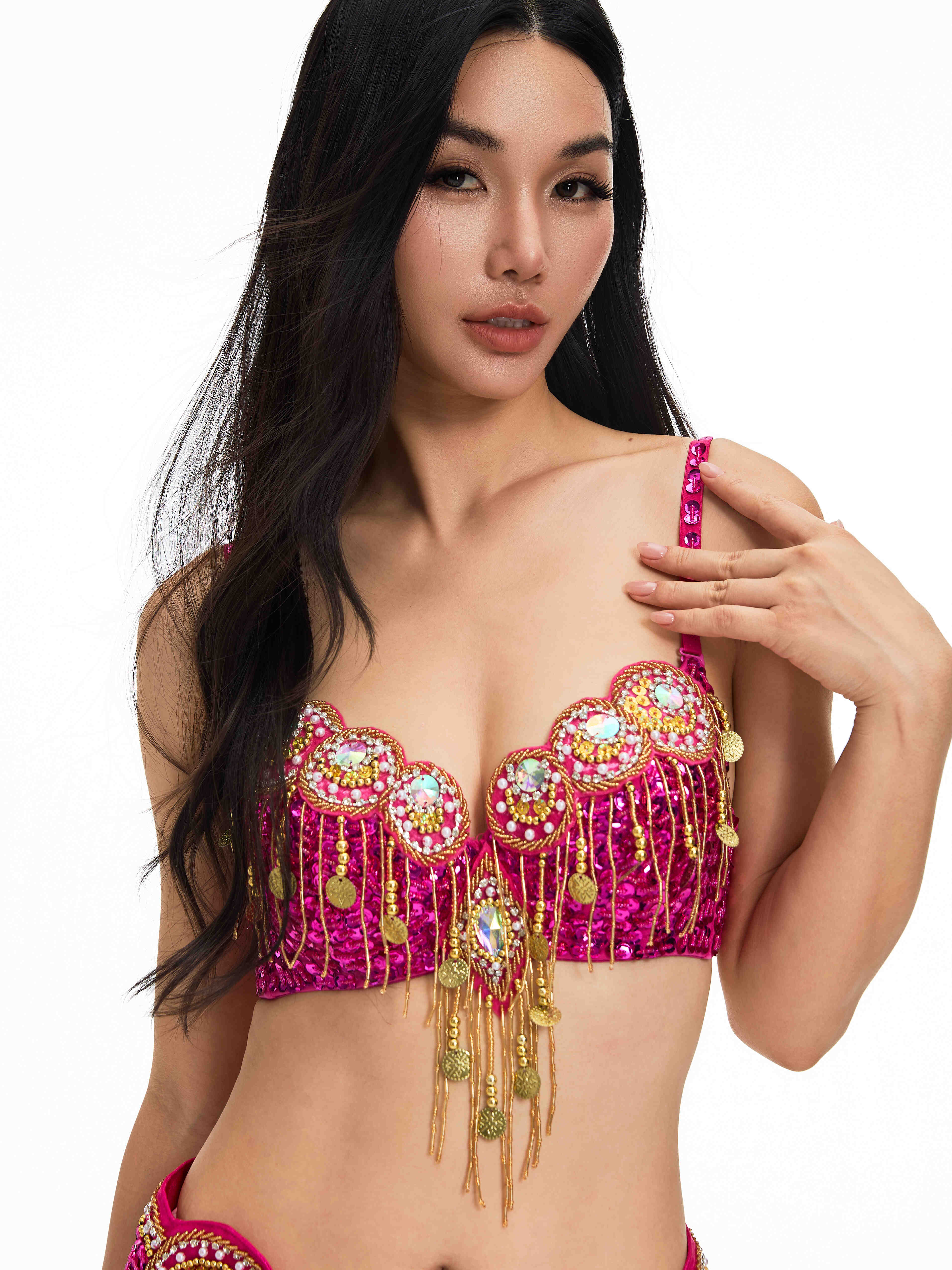 A woman poses against a white background wearing the Notics-Full Set- Rosé, a pink embellished bra adorned with gold and jewel decorations.