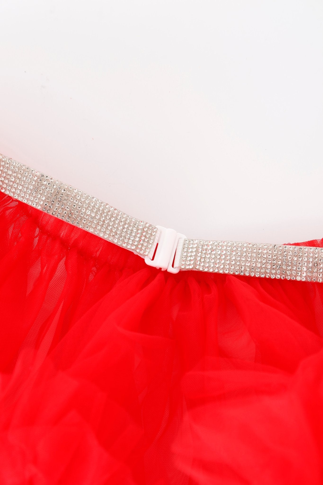 A close-up of the Poppy w Mini Skirt- Full Set, featuring a sparkling rhinestone belt with intricate rhinestone detailing and a white buckle, styled over a vibrant red tulle skirt against a plain background.