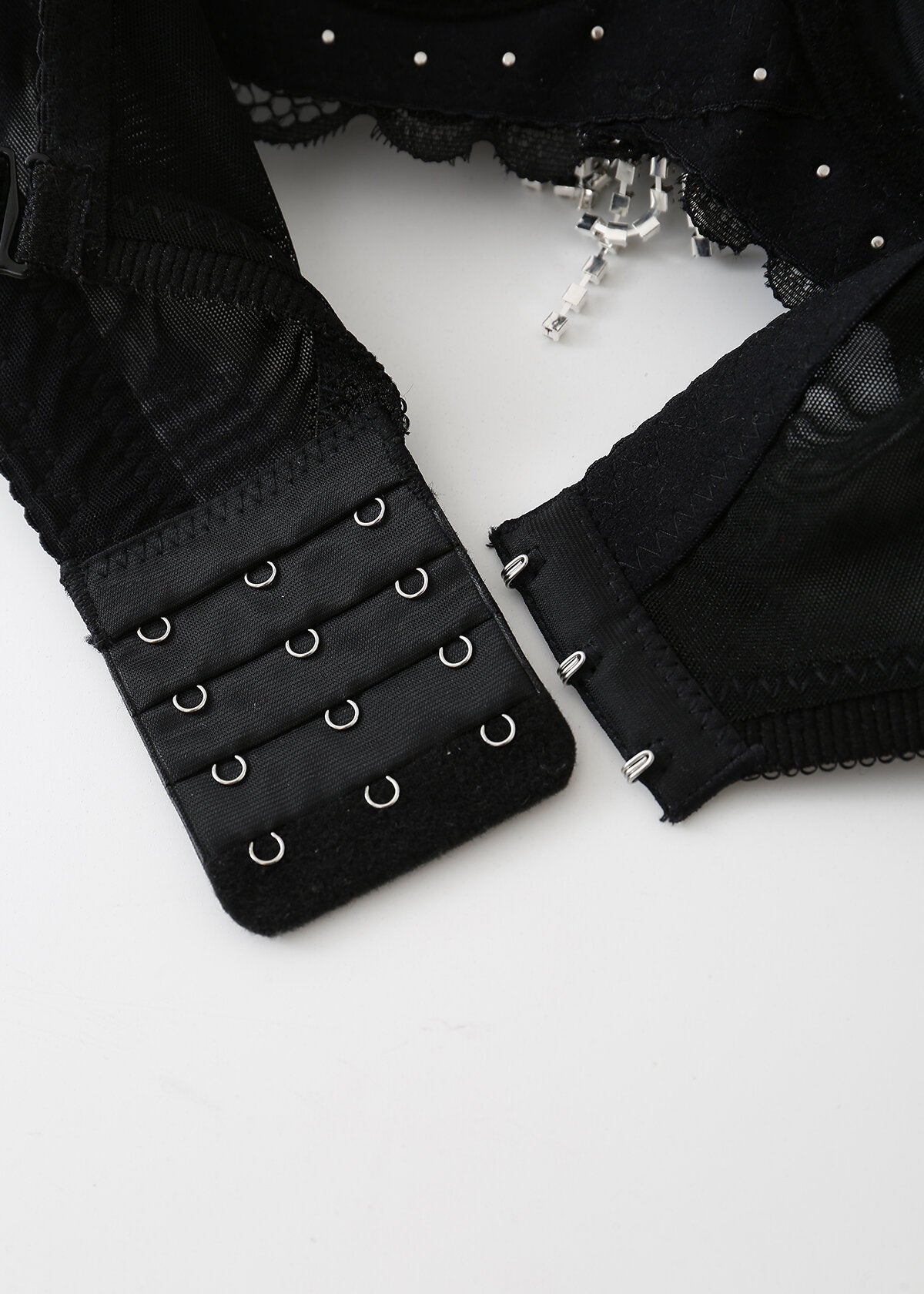 Close-up of Swan-Black-Top's handmade lace strap with three rows of unfastened hooks and eyes, featuring mesh fabric, lace trim detailing, and elegant craftsmanship.