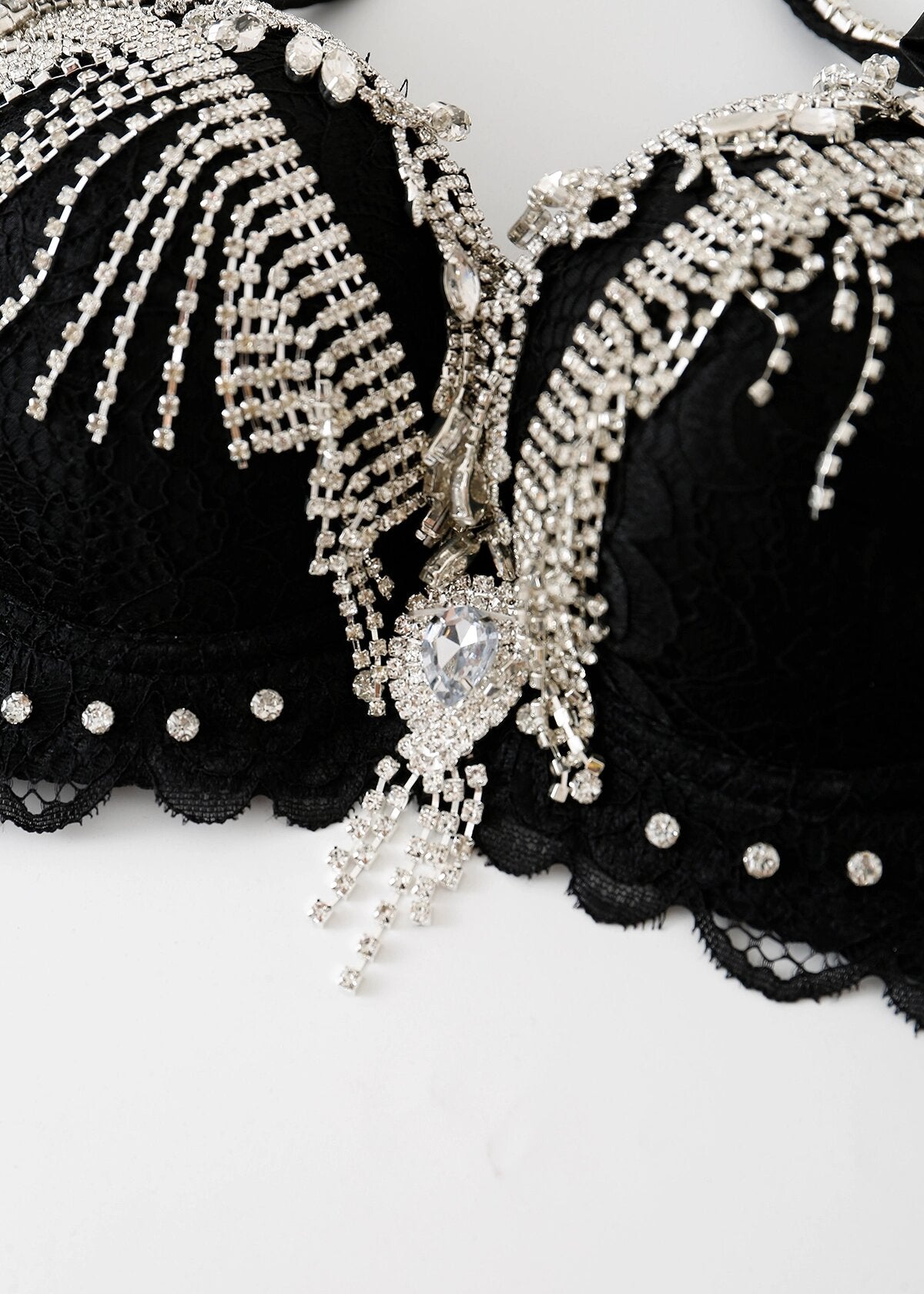 Close-up of the Swan-Black-Top, a handmade lace bra adorned with intricate silver and rhinestone embellishments and a large heart-shaped jewel at the center—a bold festival statement piece.