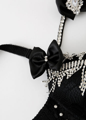 Close-up of the Swan-Black-Top, a handmade lace bra with rhinestone embellishments, sparkling fringe, and a black satin bow in the center—a perfect festival bra top.
