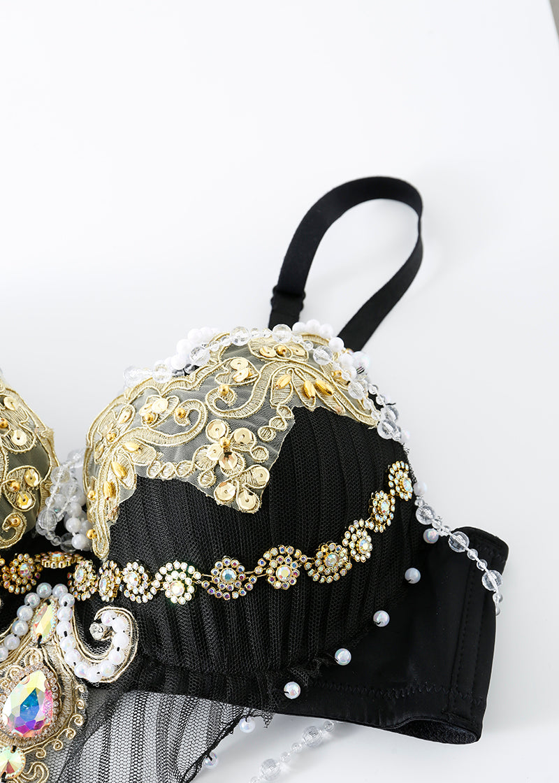 The REVERIE - Full Set - Black is a handcrafted black bra adorned with gold embroidery, sequins, pearl-like beads, and intricate embellishments—an eye-catching rave wear piece displayed on a white surface.
