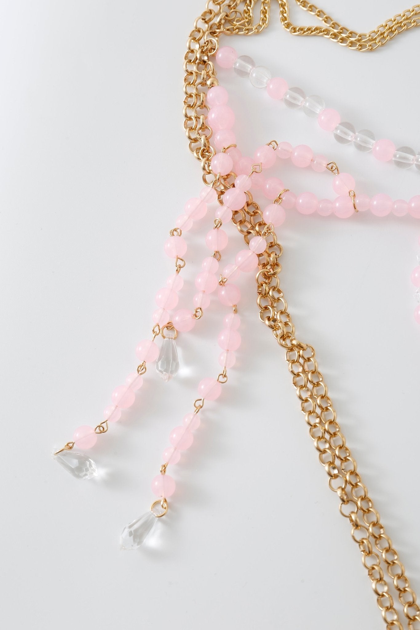 Gold chain necklace with light pink beads, clear beads, and teardrop-shaped clear pendants arranged on a white surface—an elegant accessory that effortlessly complements a beaded top or adds a delicate touch when layered over your Rosette w Pashmina- Full Set.
