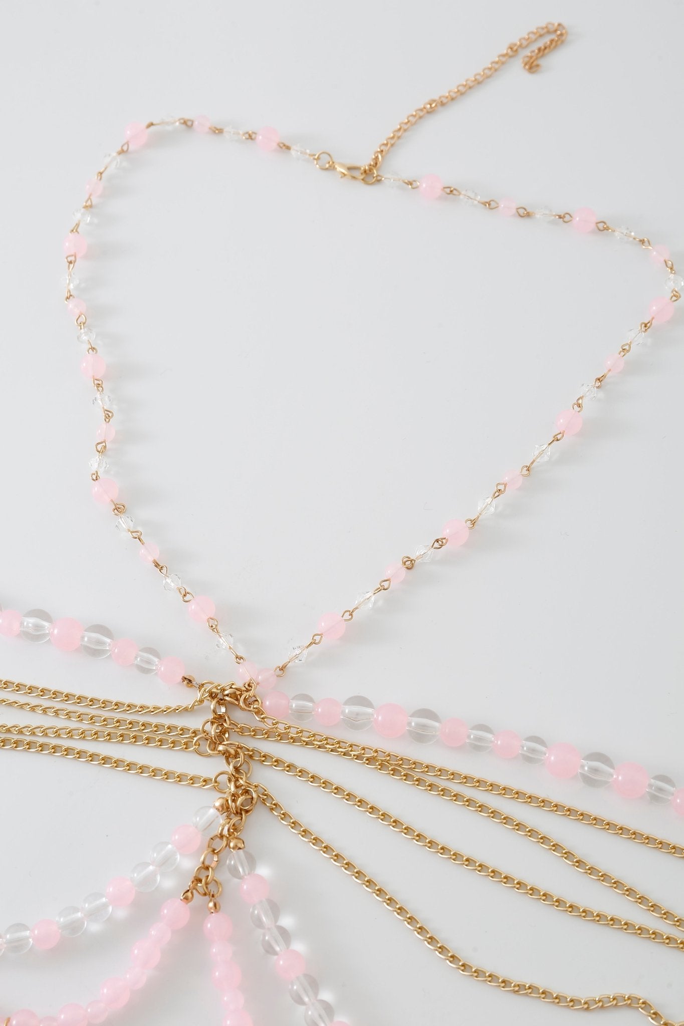 Rosette w Pashmina- Full Set displayed on a white surface features multiple gold chain strands accented with pink and clear beads, all attached to a central clasp for a layered, delicate look reminiscent of an elegant beaded top.