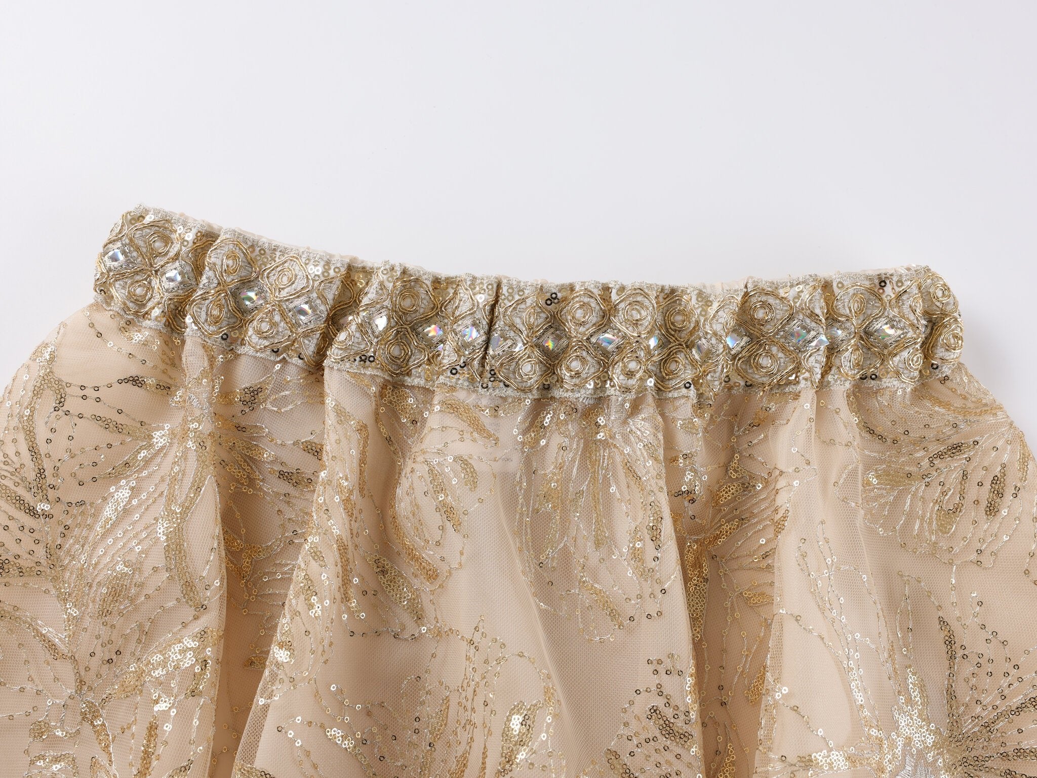 Close-up of the Selene-Full Set-Gold skirt: a beige design adorned with gold sequin embroidery, an ornate beaded waistband, and delicate rhinestone fringe—perfect for making a statement at any festival. Photographed on a white background.