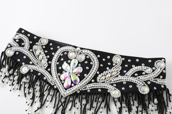 The Velora- Black- Bottom is a black fabric belt featuring iridescent rhinestones in swirling patterns and black beaded fringe along the edge, perfect for pairing with a beaded fringe skirt or a sleek black satin mini.